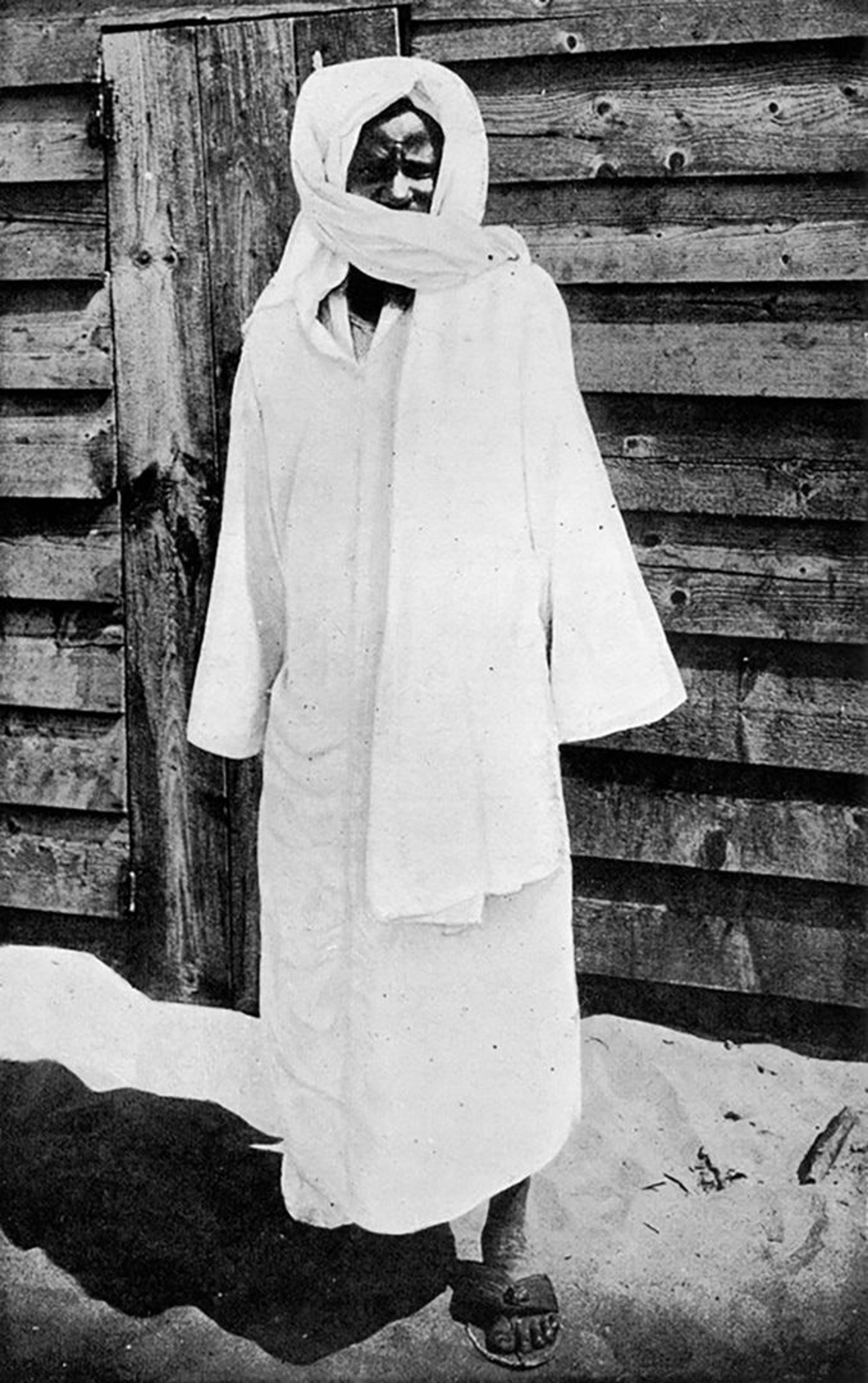 A black-and-white photo of a man shrouded in all-white cloth