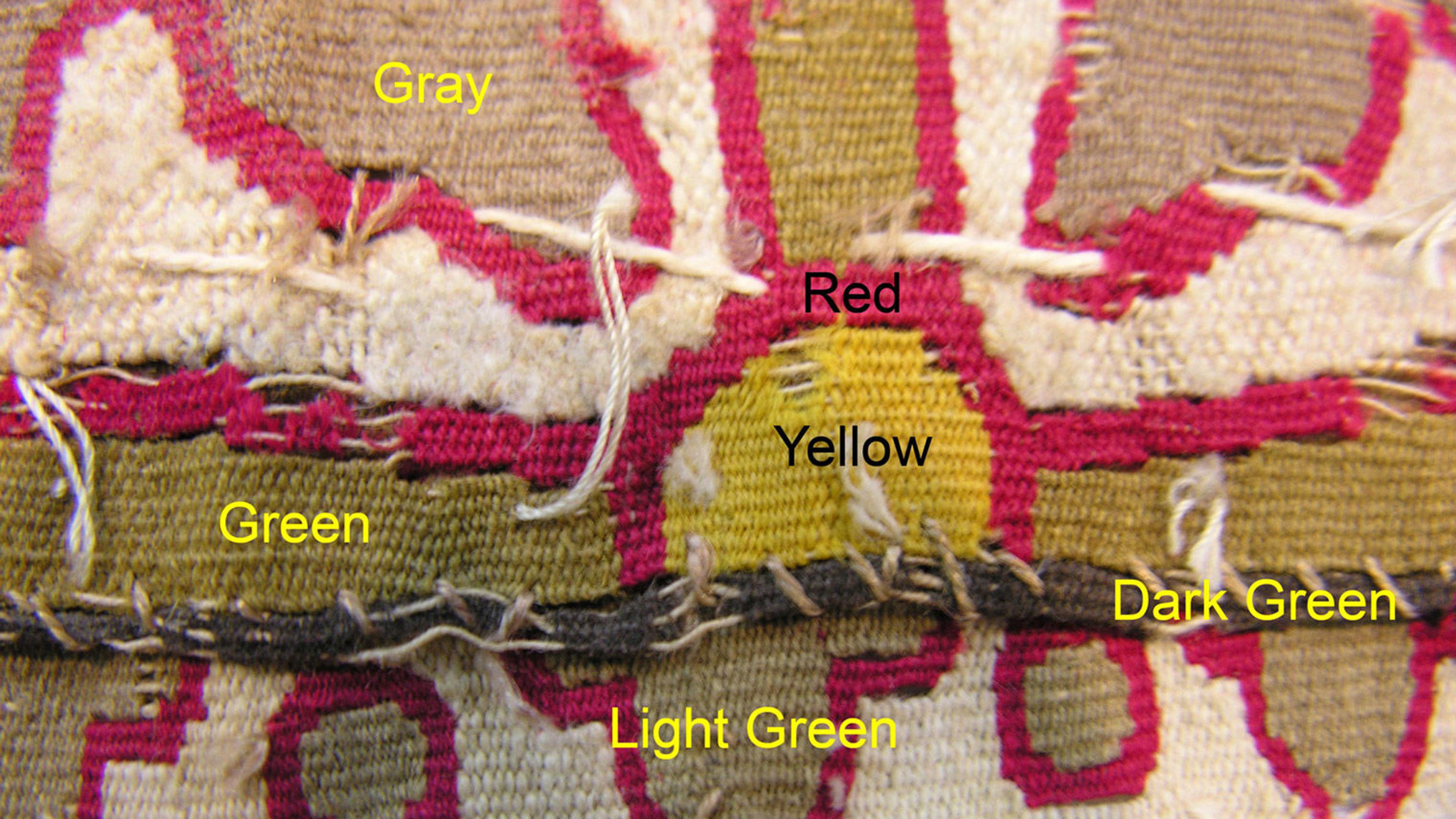Macro image of a tapestry labeled with the colors "Gray, Red, Green, Yellow, Light Green, and Dark Green."