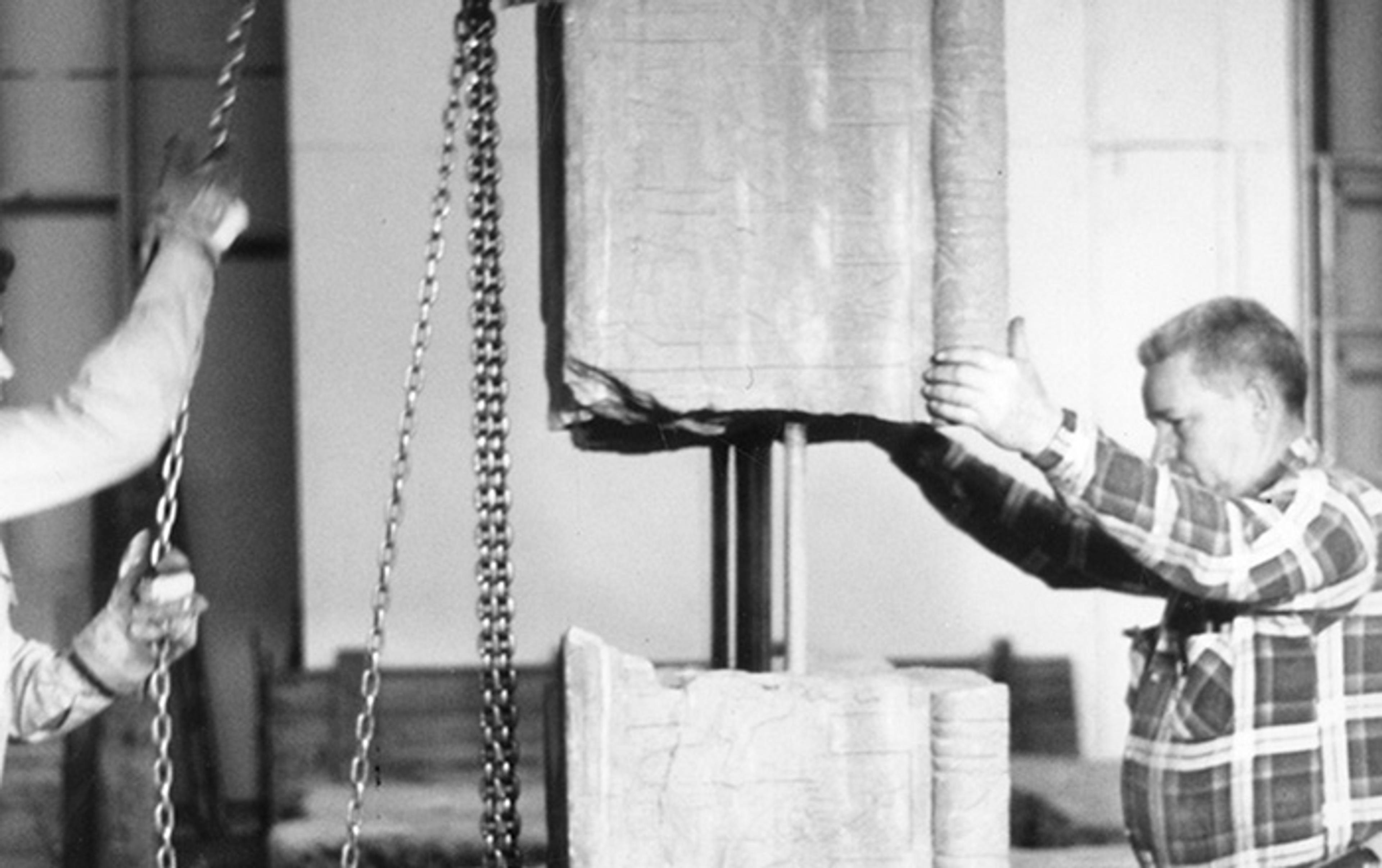 Black and white photograph of two people joining fragments of a block from the Temple of Dendur prior to its reassembly in the 1970s