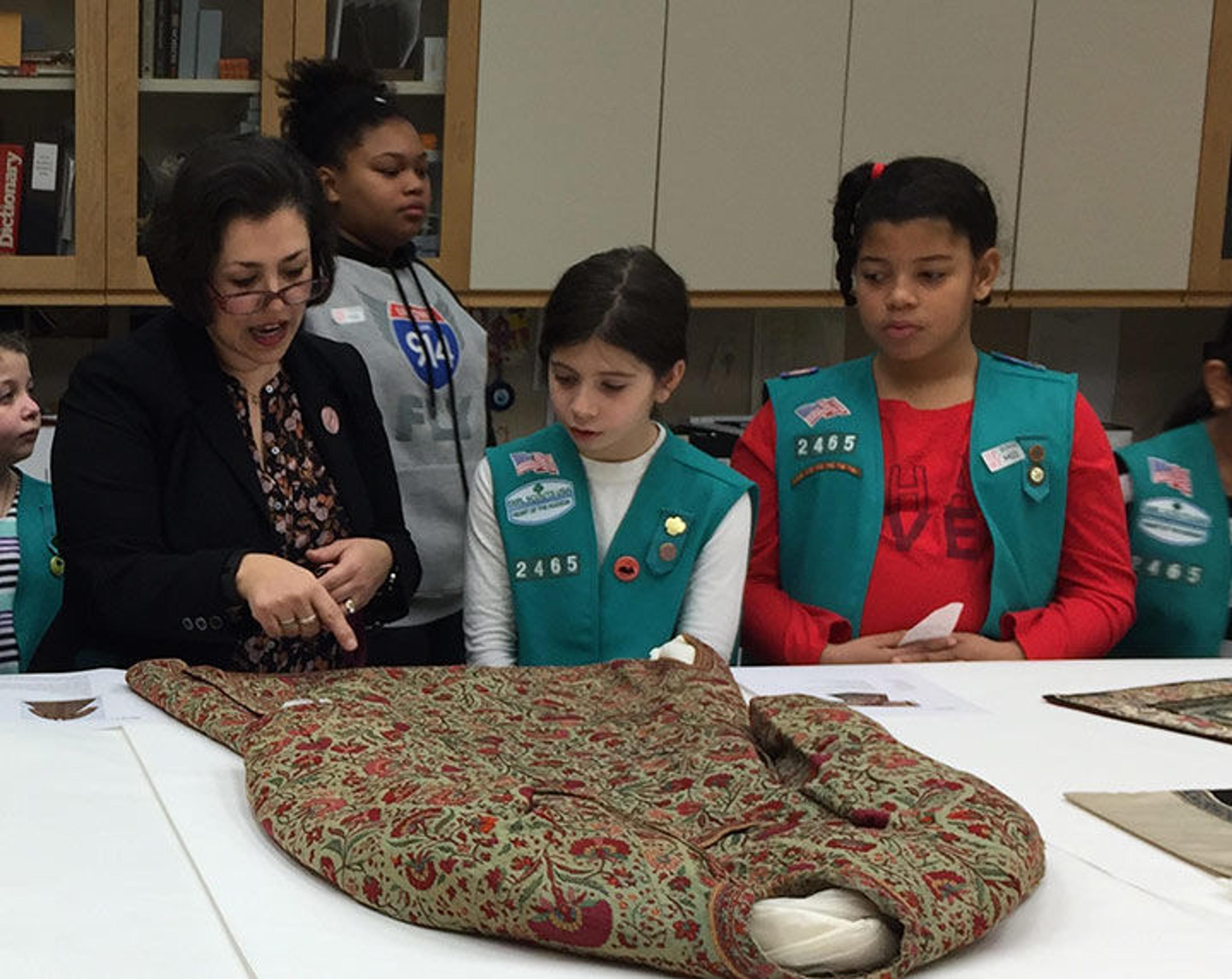 Giovanna shows the Girl Scouts an embroidered coat