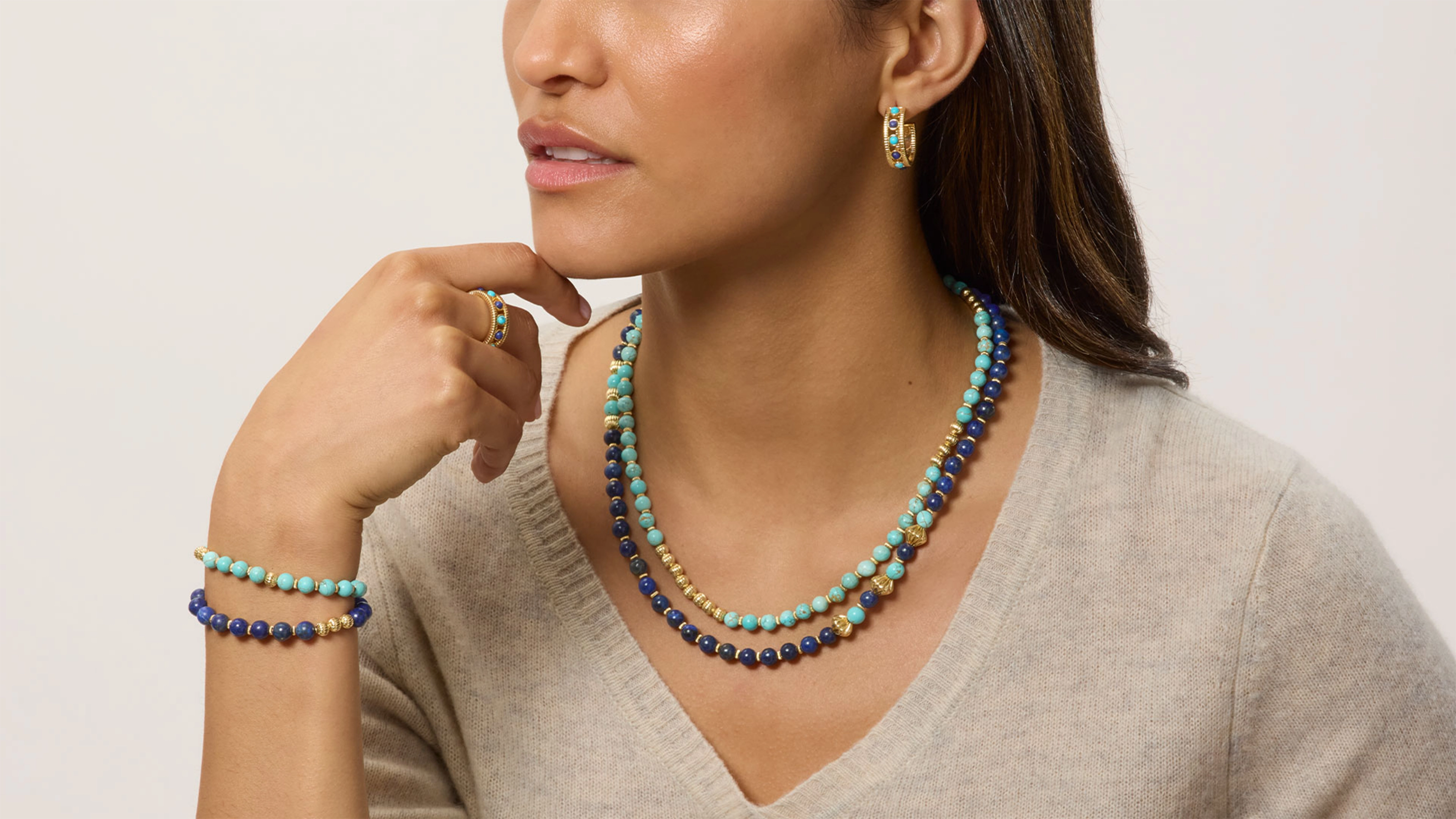 A person wearing a stack of colorful necklaces and bracelets.