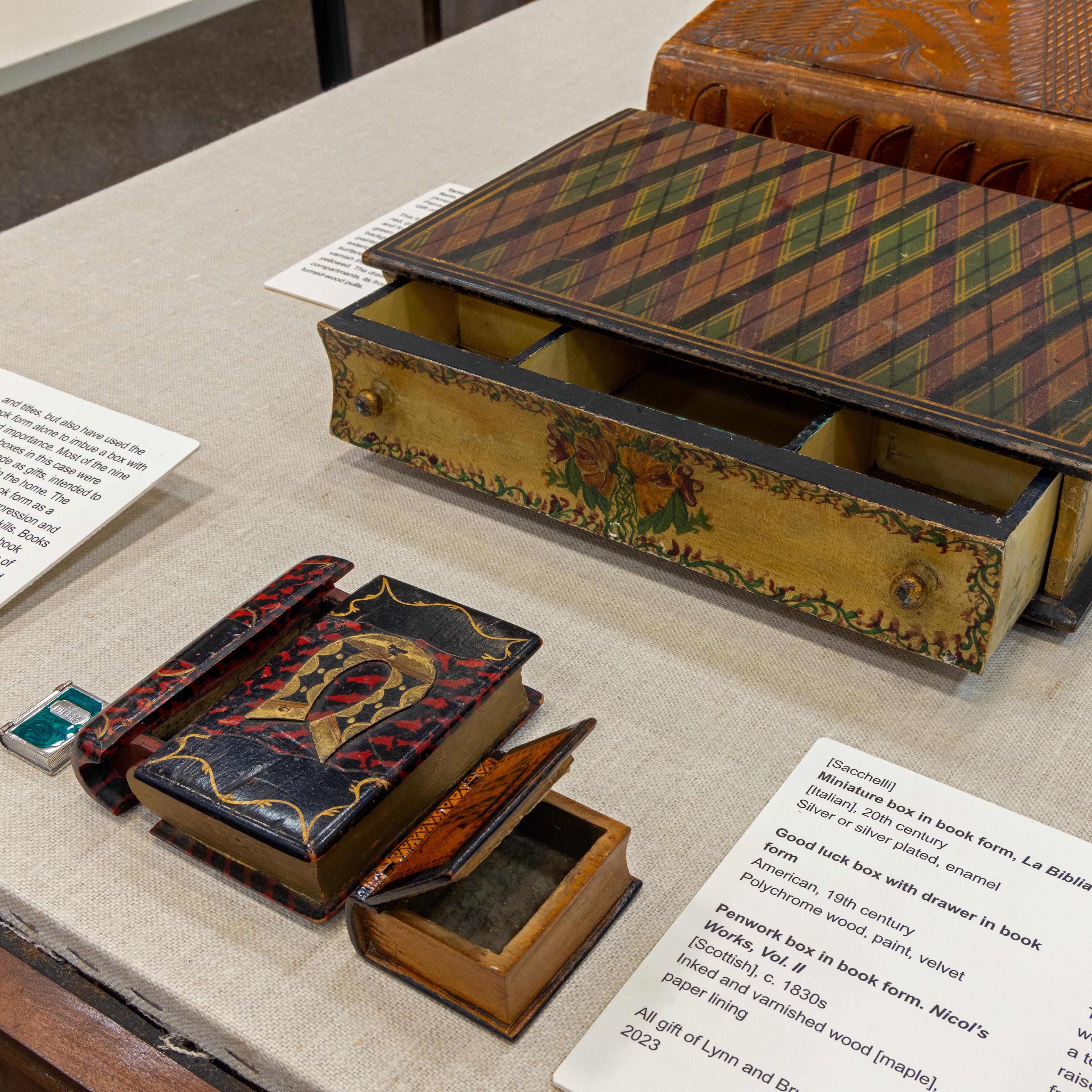 A set of three antique, graduated, stackable wooden boxes, each with a curved lid, painted in a distressed red with faint foliage motifs, featuring a central metal pull handle, resting on small, stylized feet.