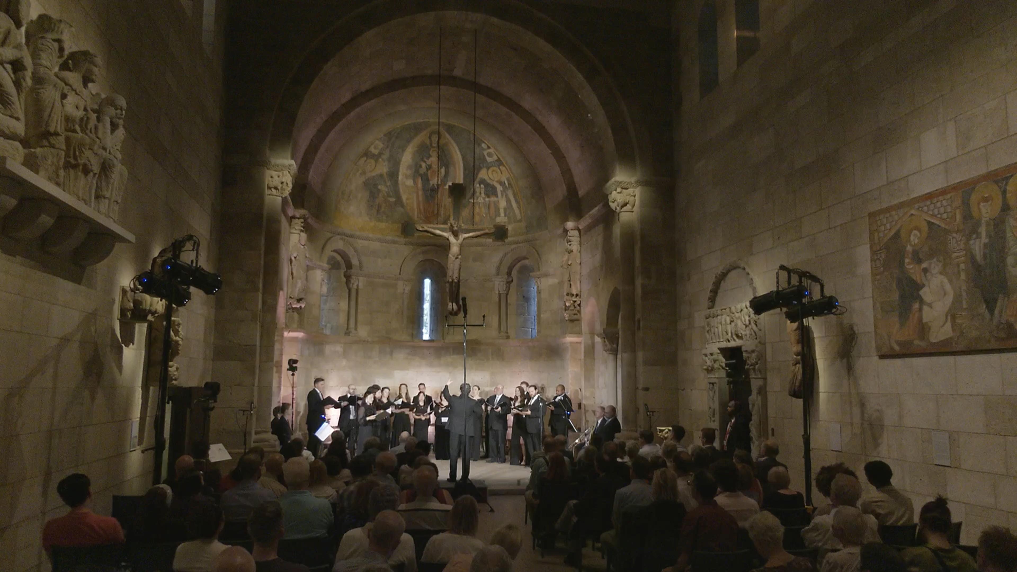 An audience watches a choir onstage in the Fuentidueña Chapel