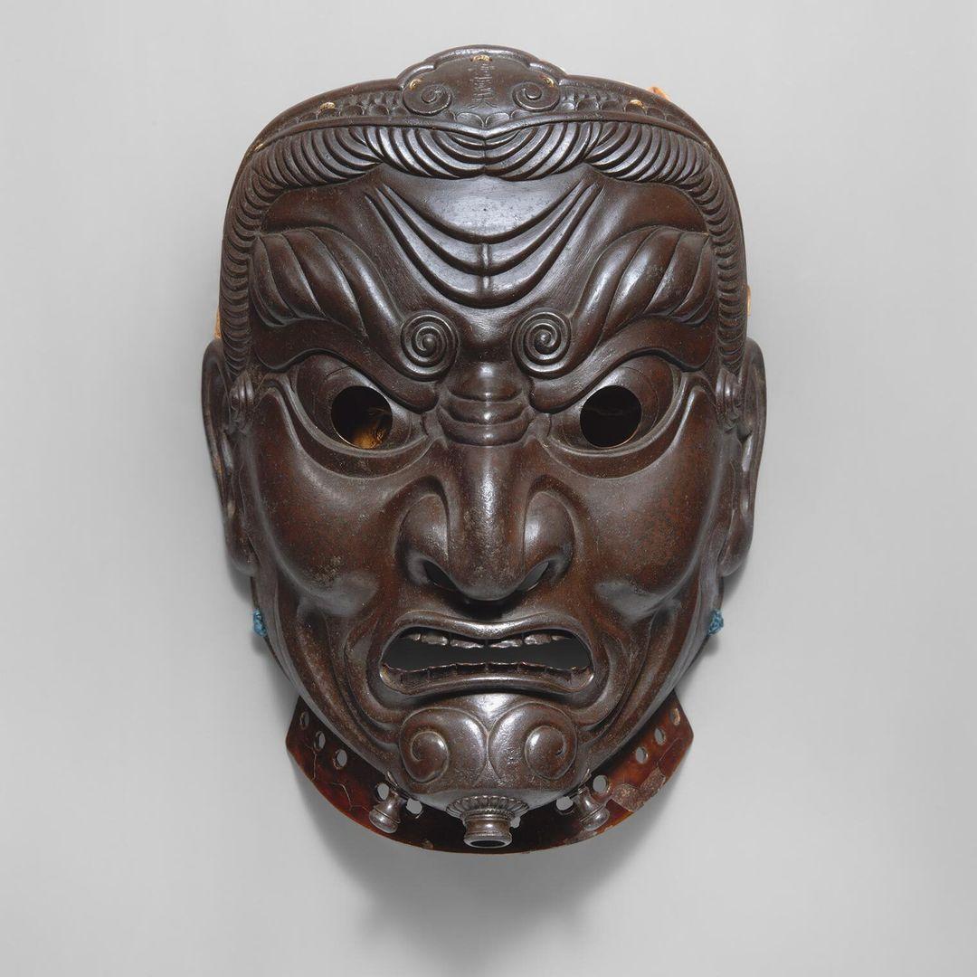 A metal mask depicting a fierce scowling god