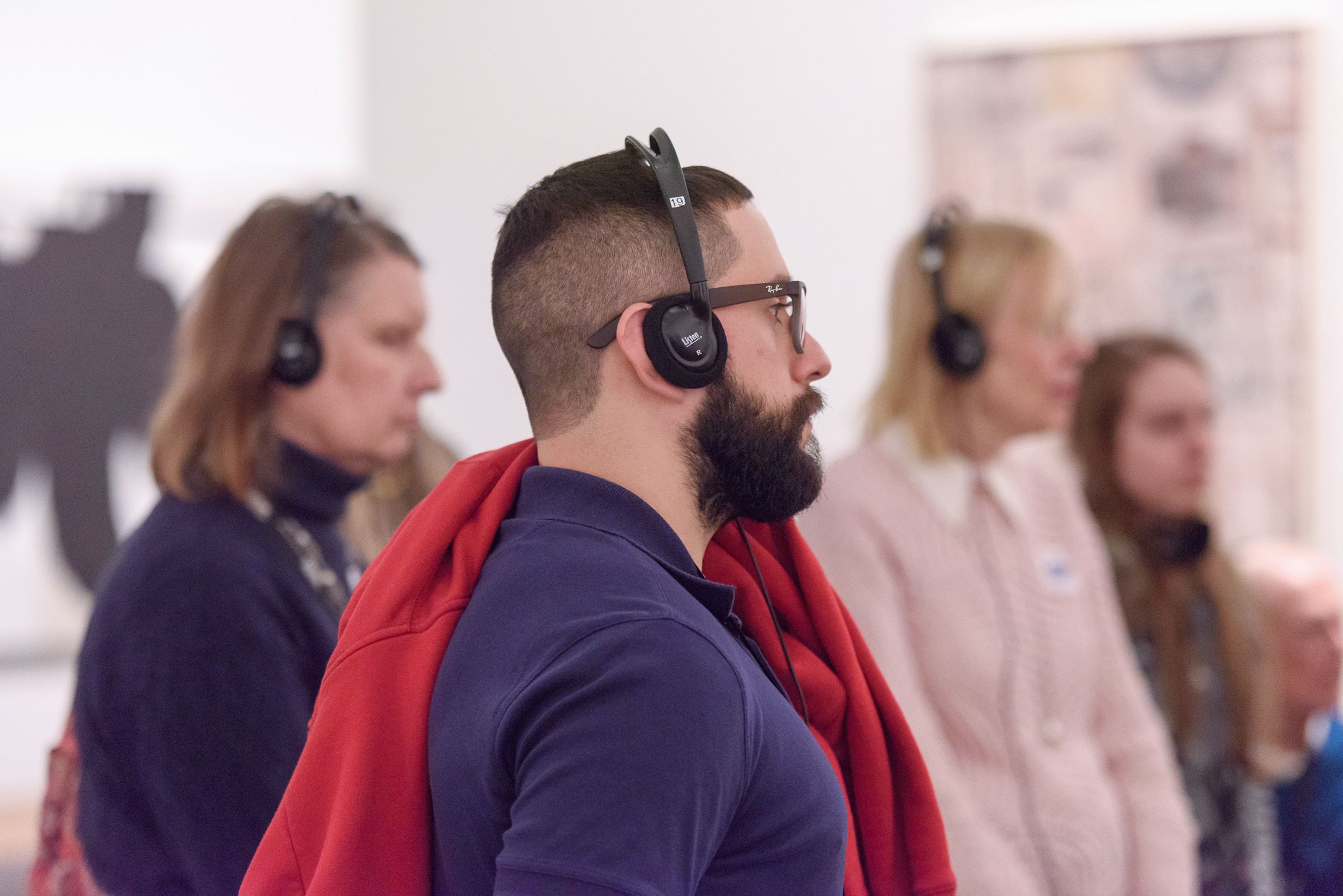 A young man with a beard wears over the ear headphones.