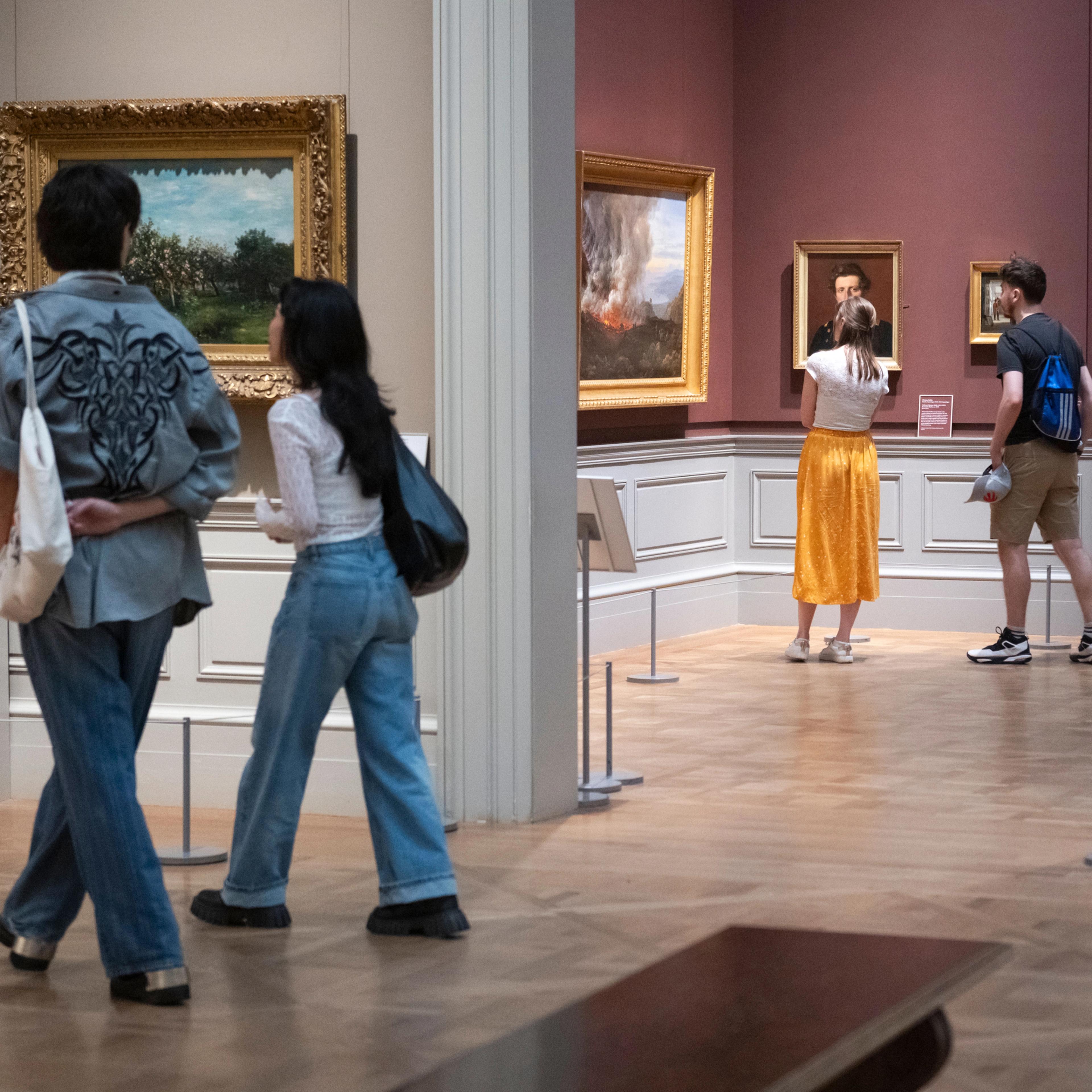 Visitors admiring paintings displayed on the walls