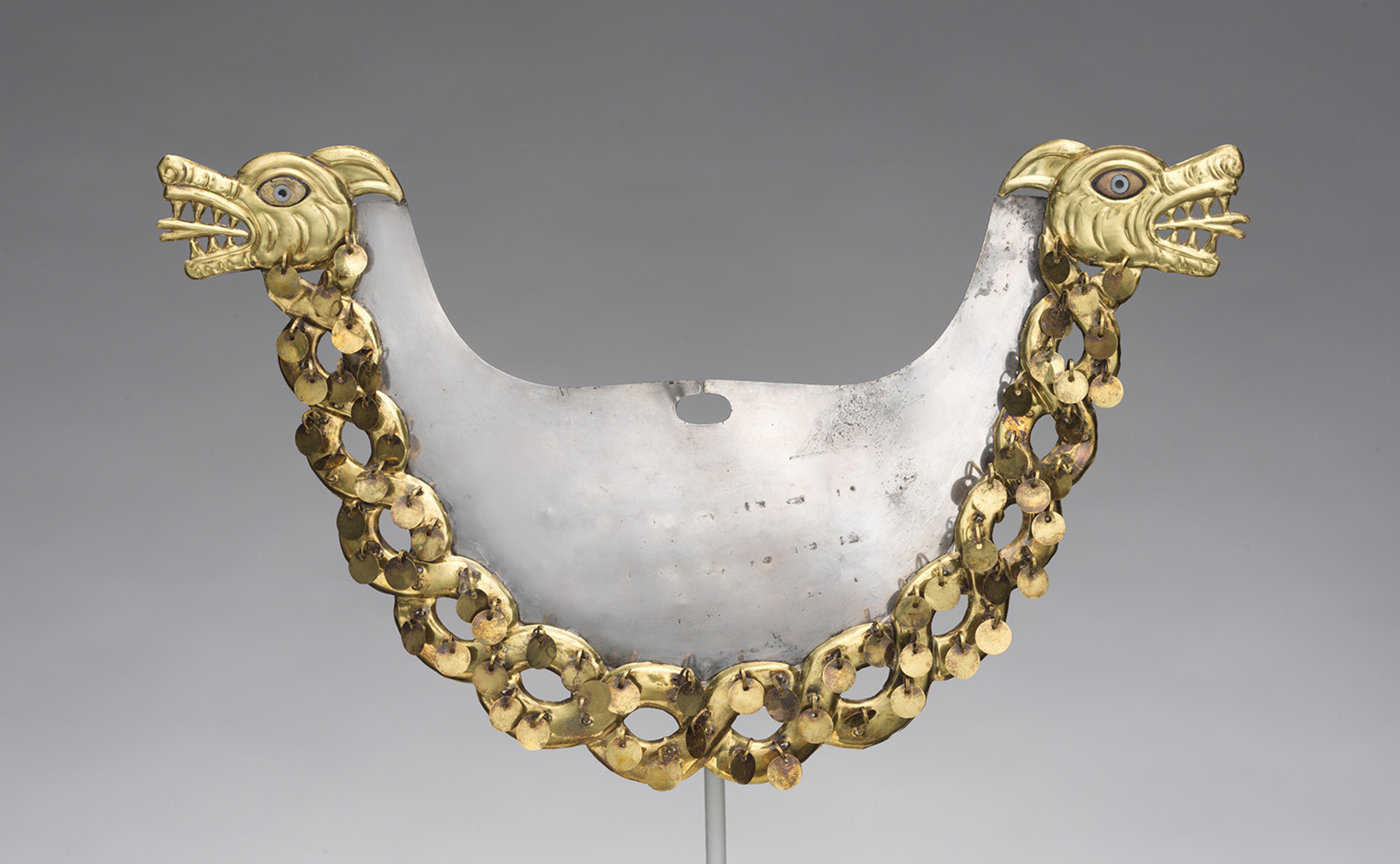 An ornate metal breastplate with two dragon heads, detailed with gold and blue accents. Connected by a chain of gold links