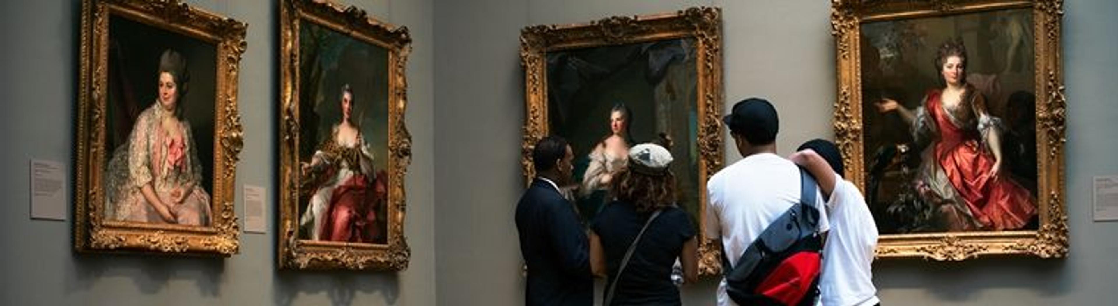 A group of museumgoers look at European paintings on view in a gallery