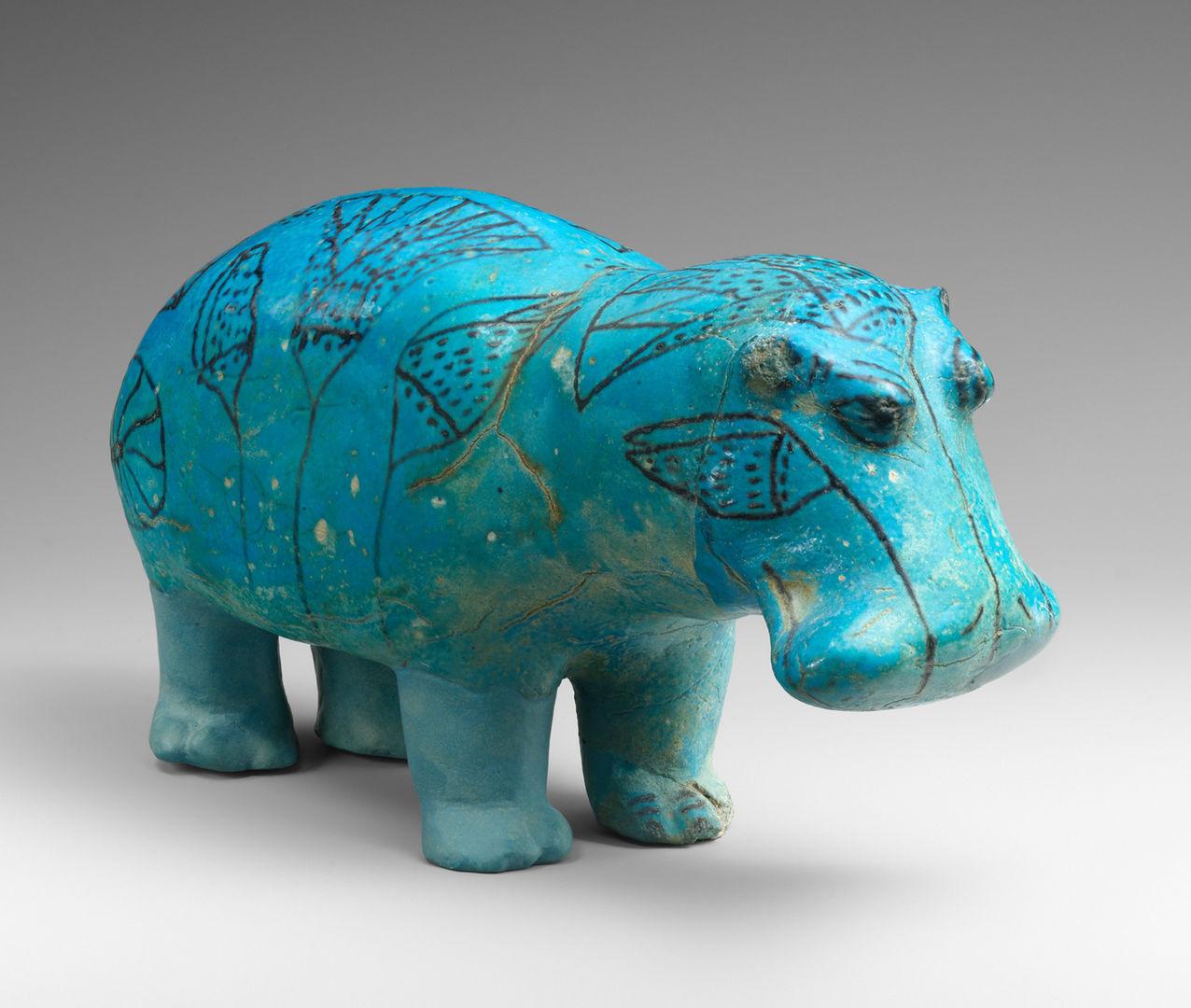 A small blue hippopotamus sculpture with detailed facial features and floral leaf outlines on the back and head.