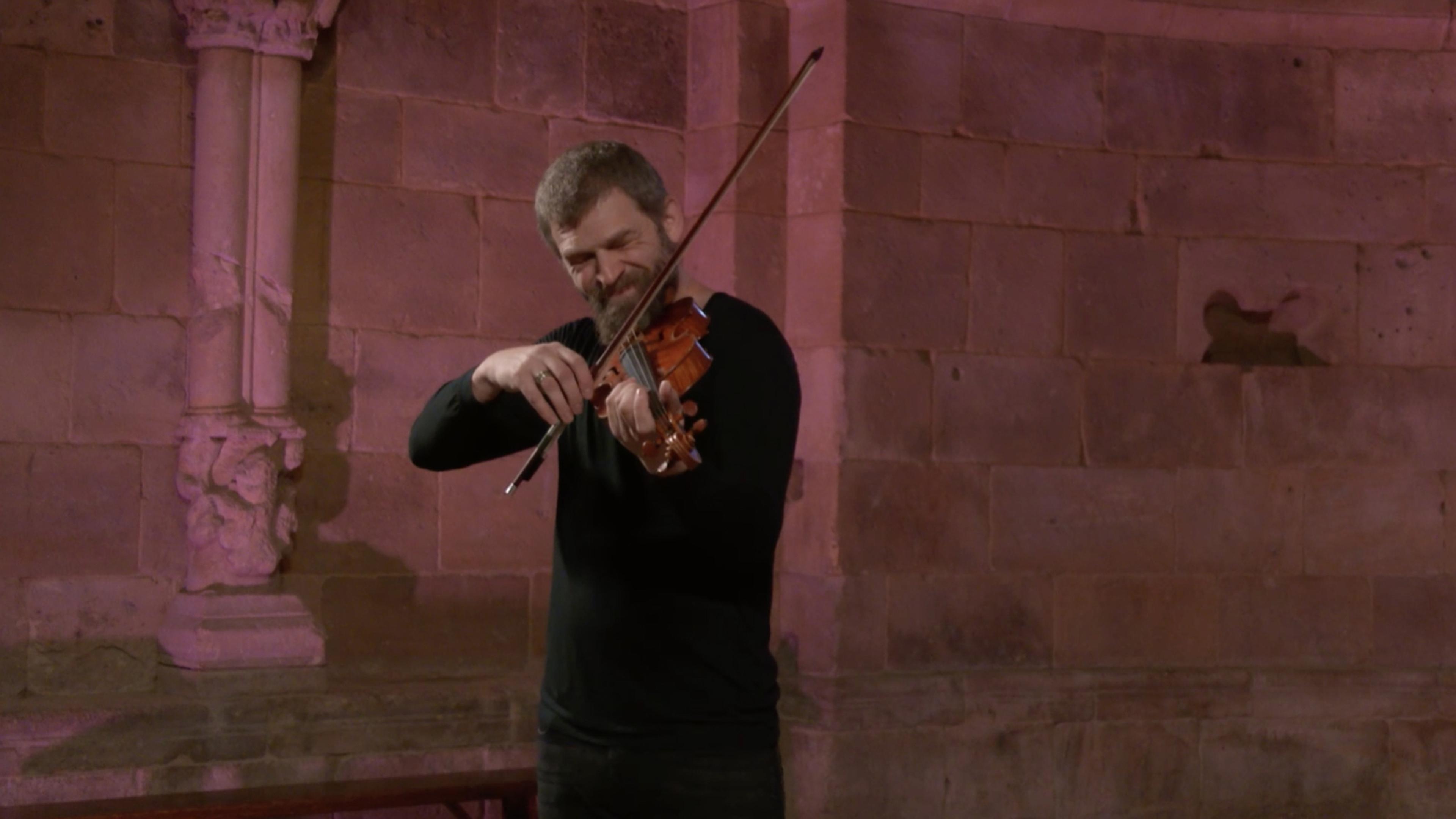 A smiling Johnny Gandelsman plays the violin.