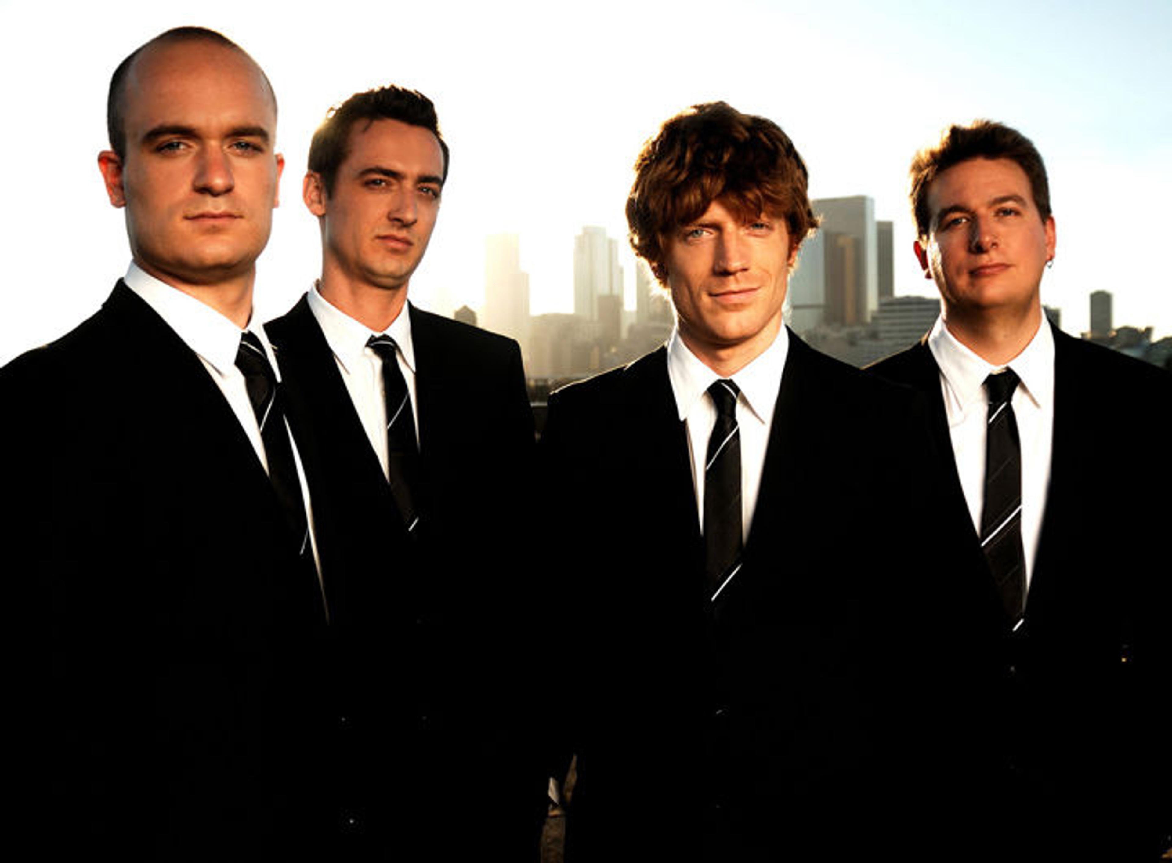 The four members of the Calder Quartet in black suits against an urban skyline