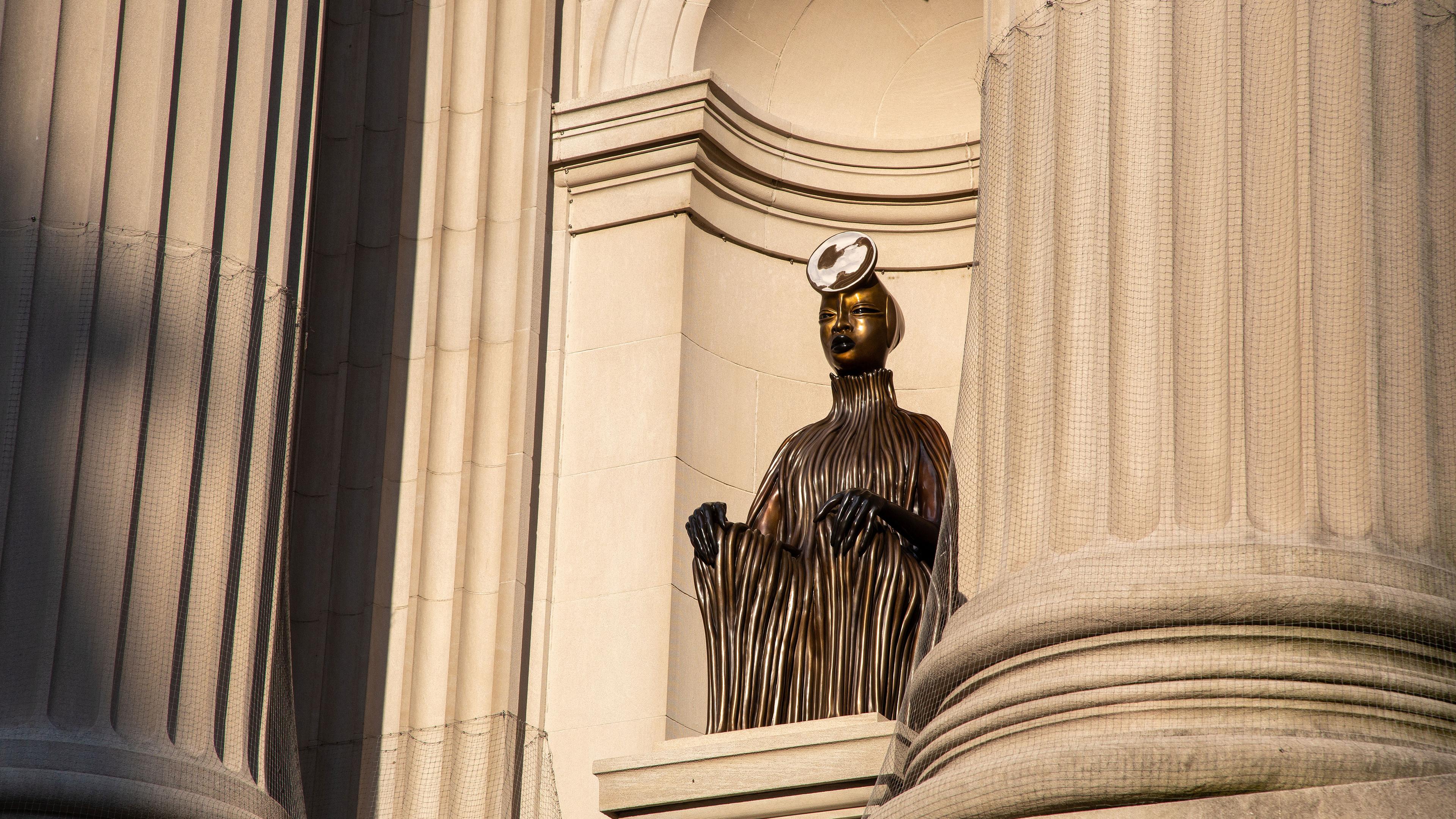 A bronze figure sits in a niche in the facade of The Metropolitan Museum of Art