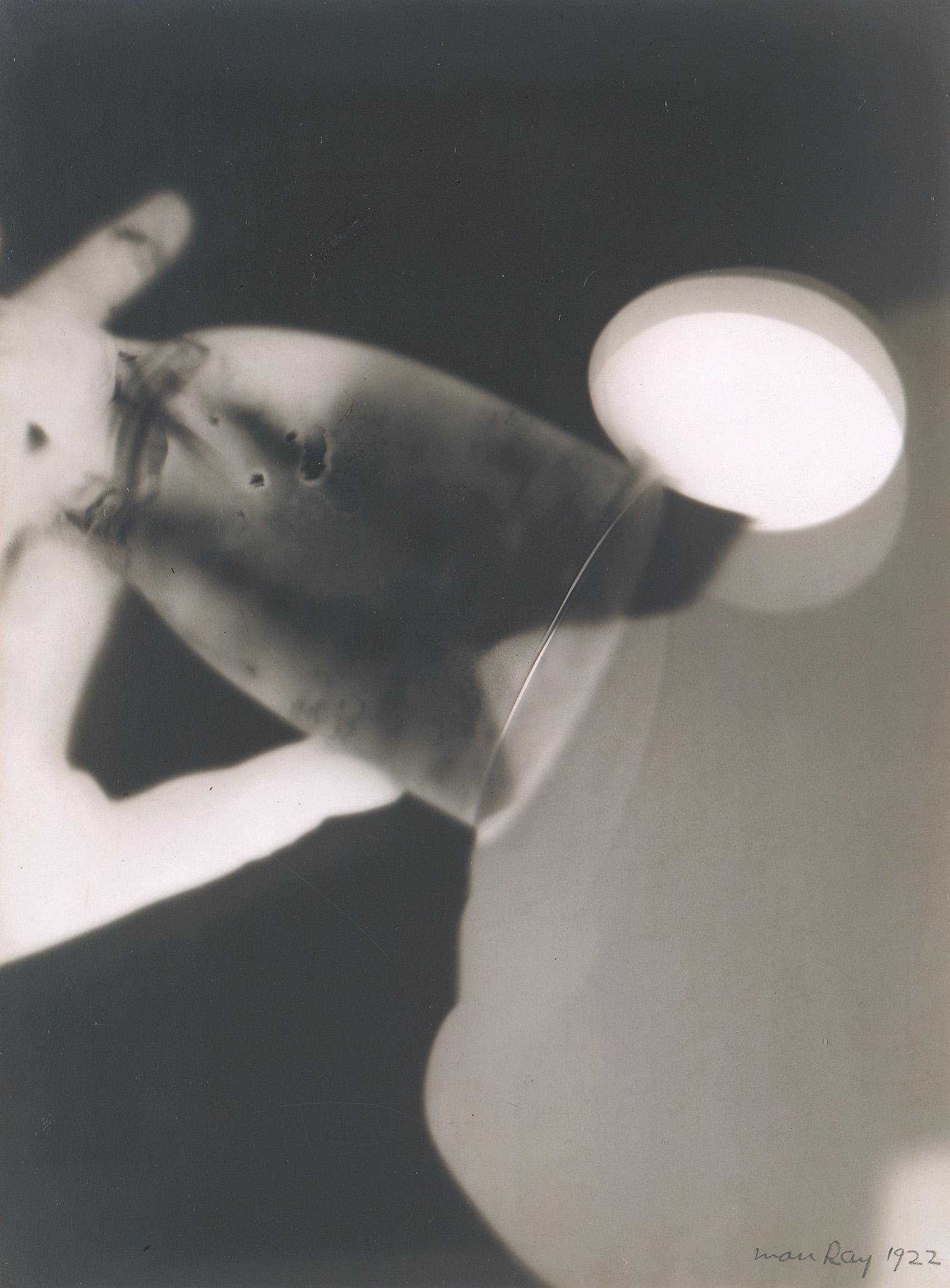 Abstract black-and-white photogram by Man Ray. It features blurry circular shapes and overlapping shadows, conveying a dreamy, ethereal tone.