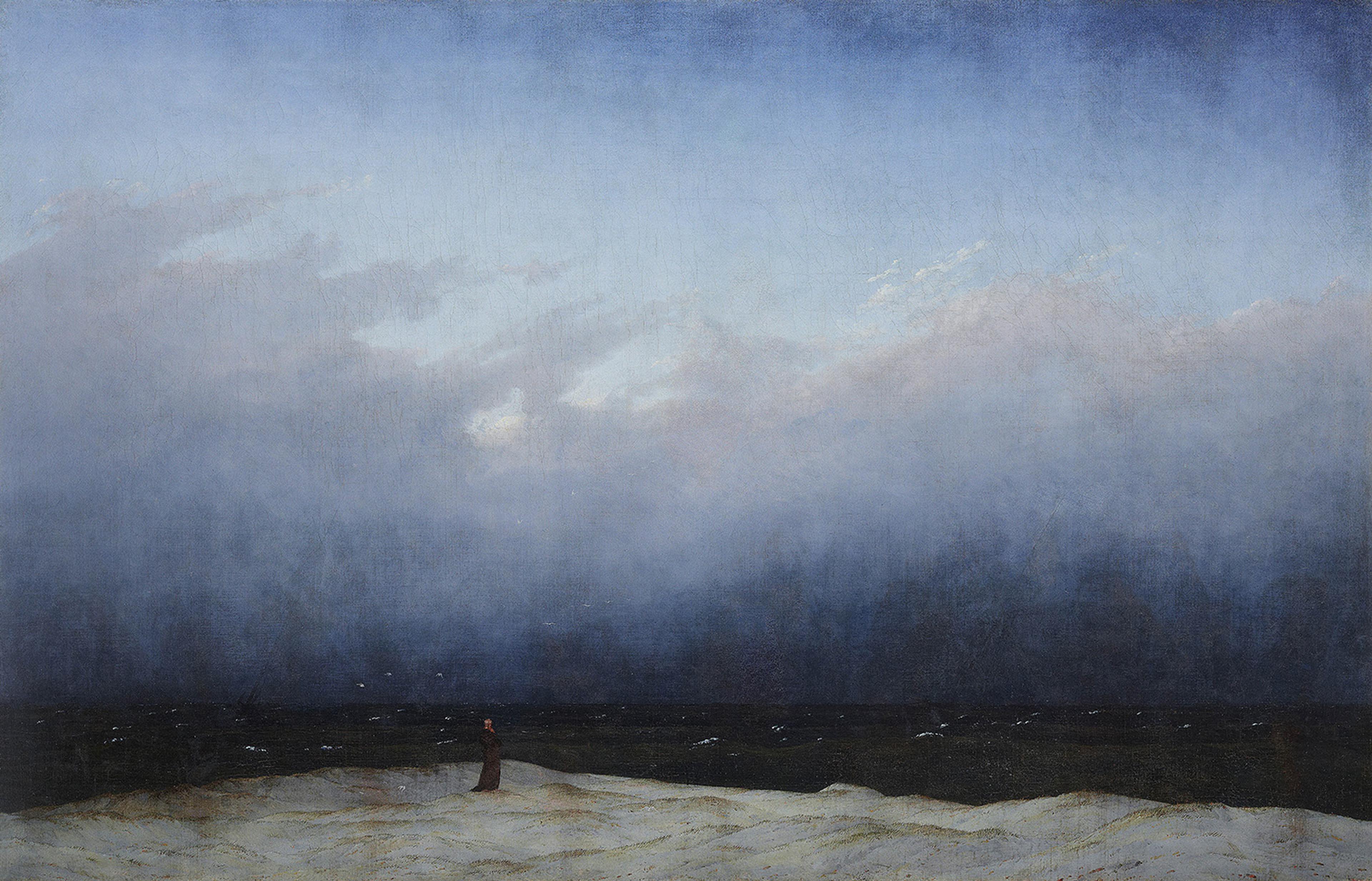 A solitary figure stands on a dune, gazing at the vast, dark sea under a cloudy sky.