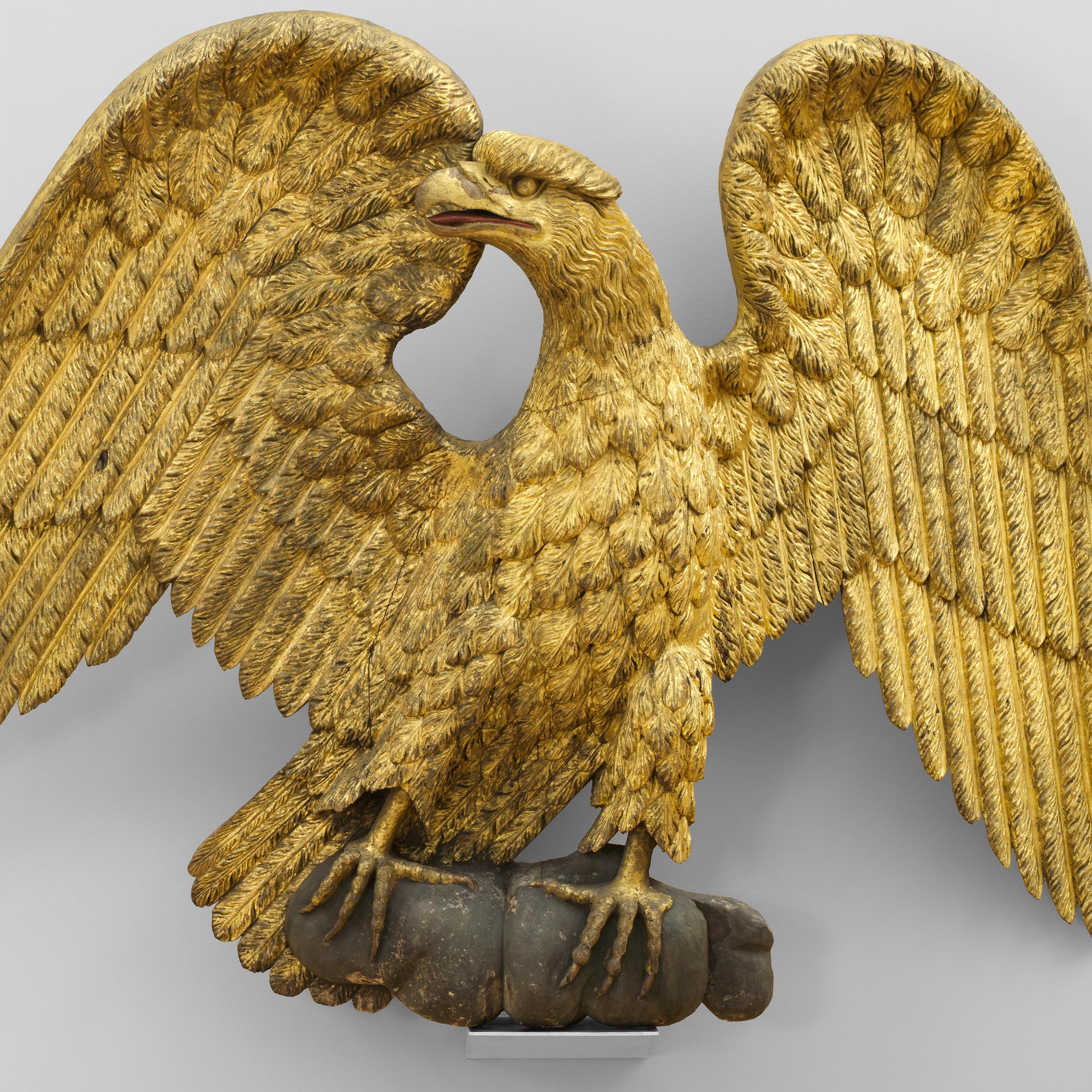 Figure of an eagle, gold sculpture with wings open, looking to the left