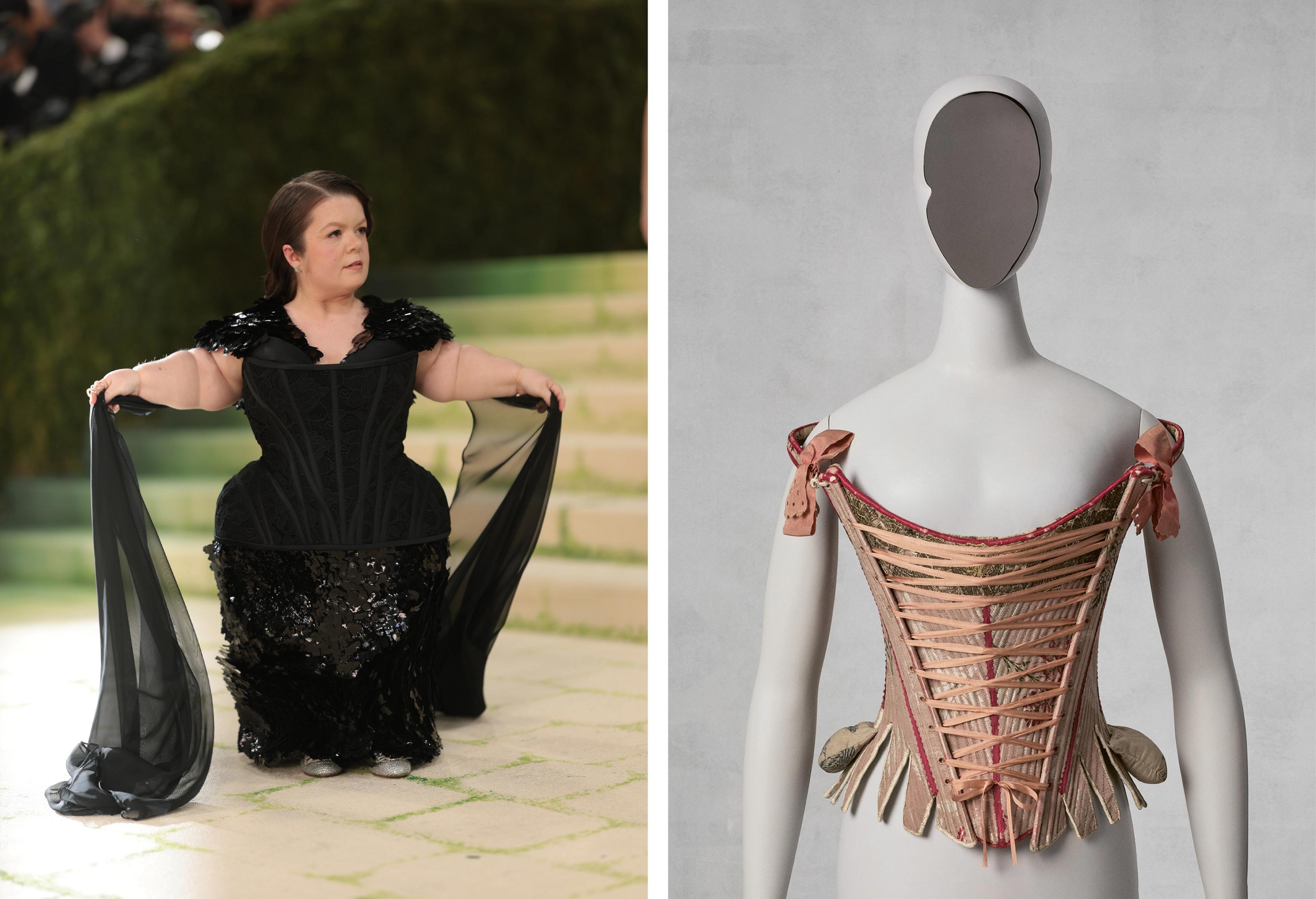 A person in an elegant black gown with sheer black sleeves poses confidently on a green-carpeted staircase. Next to it, a mannequin displays a vintage pink laced corset against a gray background.