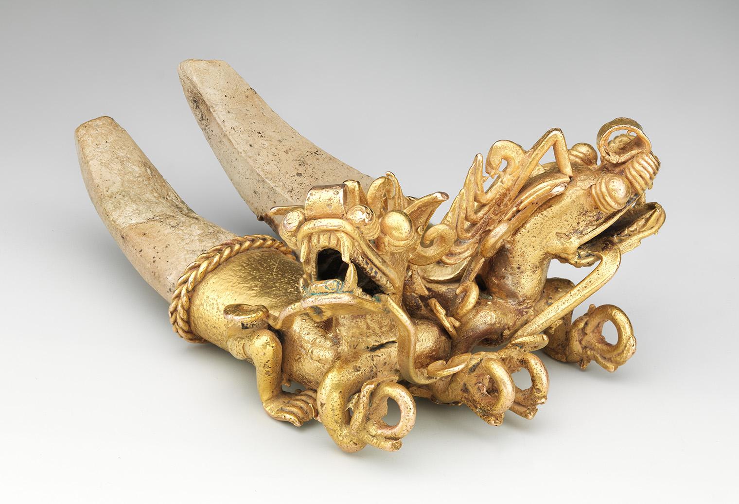 Gold ornament depicting two detailed, intertwined dragons with elongated horns and intricate carving