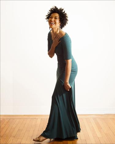 Julia Bullock standing in a green dress against a white wall