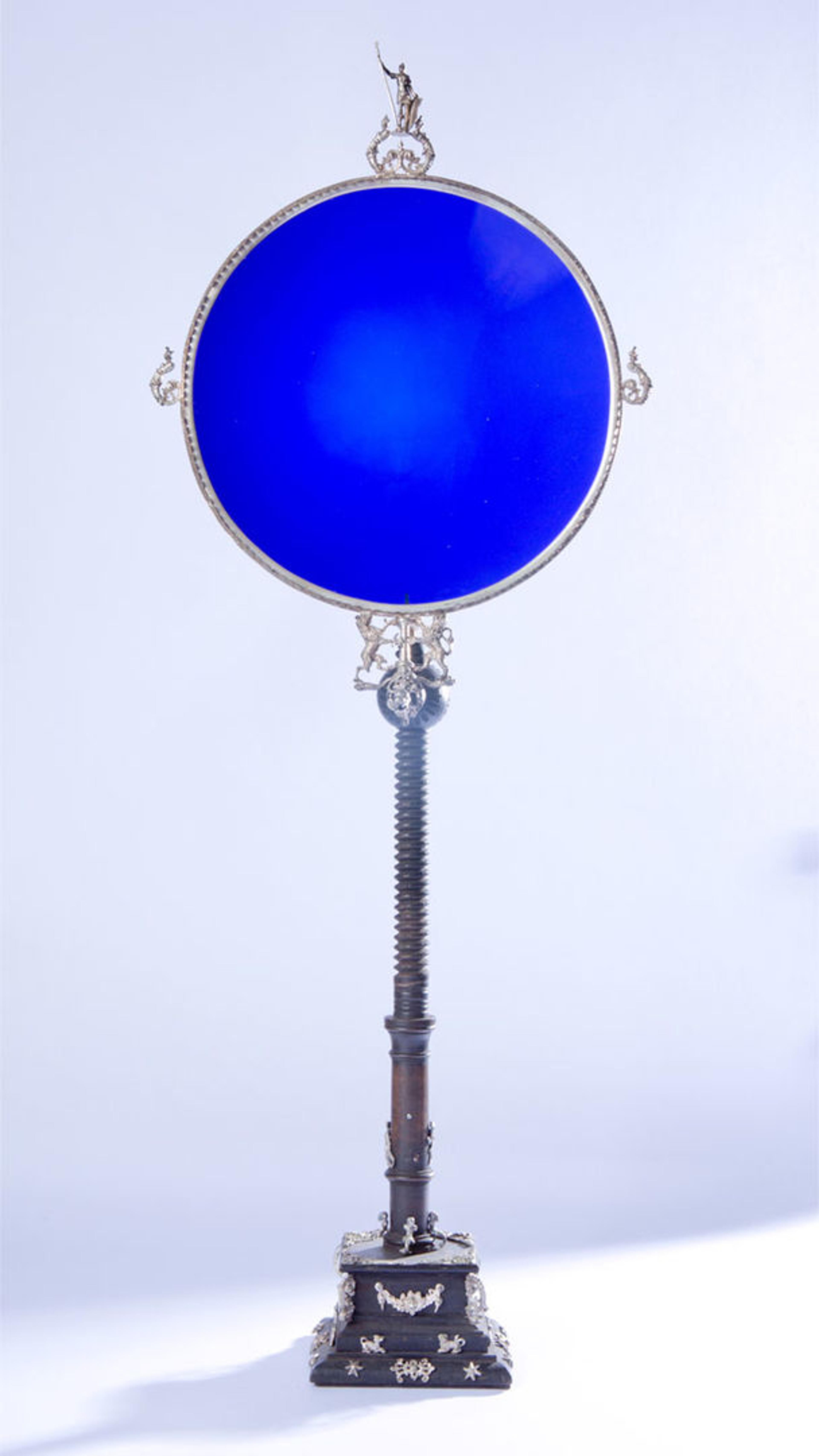 A solar observation shield with blue glass on pearwood stand with figures carved in silver