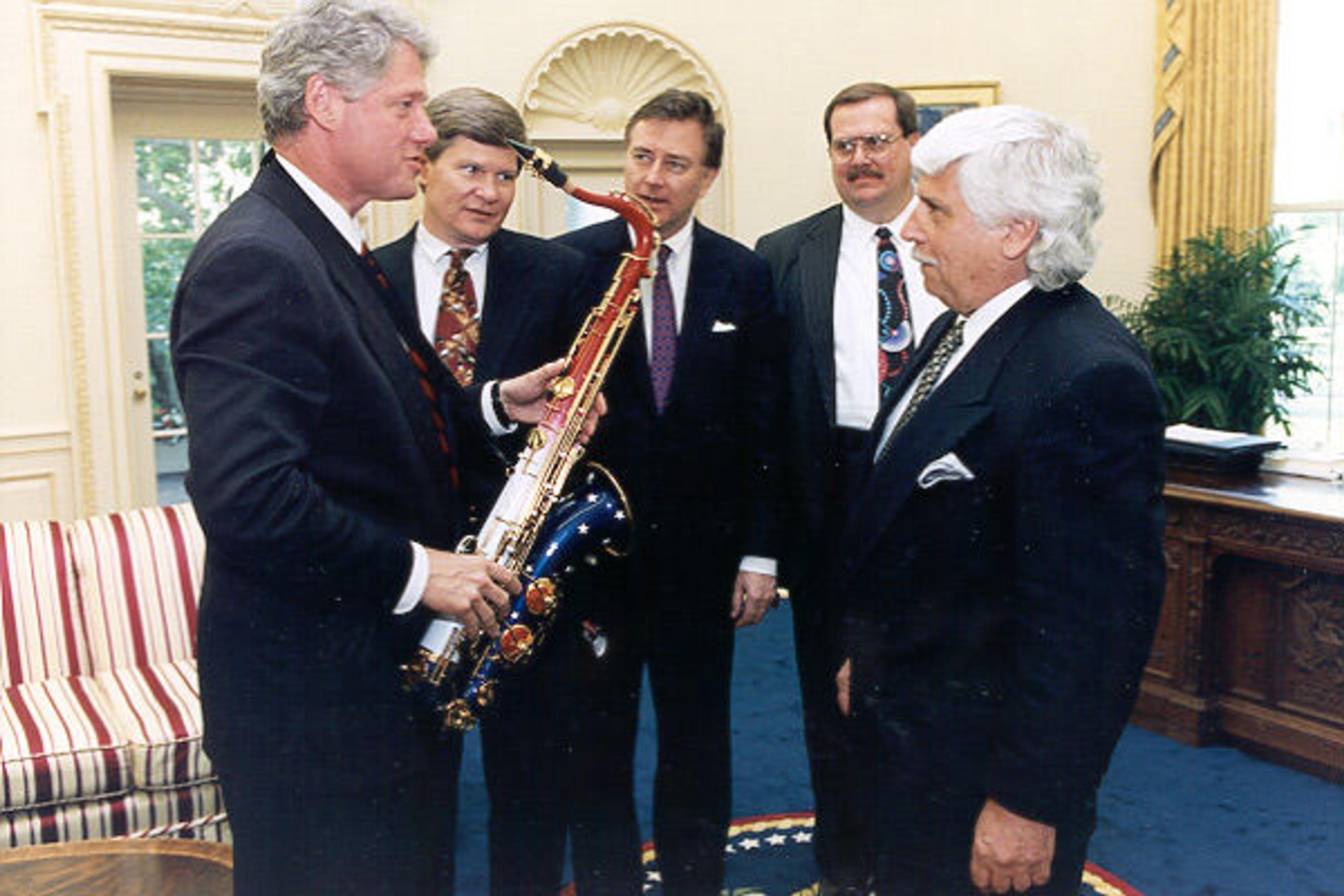 President Bill Clinton accepts the limited-edition Presidential Model tenor saxophone built in his honor by the L.A. Sax Company, Barrington, Illinois. Peter LaPlaca, president and CEO of L.A. Sax, made the presentation to Clinton in the Oval Office on May 16, 1994. Witnessing the presentation were (left to right) Congressman Tim Johnson (D-SD), Senator Larry Pressler (R-SD), and John Hilbert, vice president for University Relations, University of South Dakota. Photograph courtesy of the White House