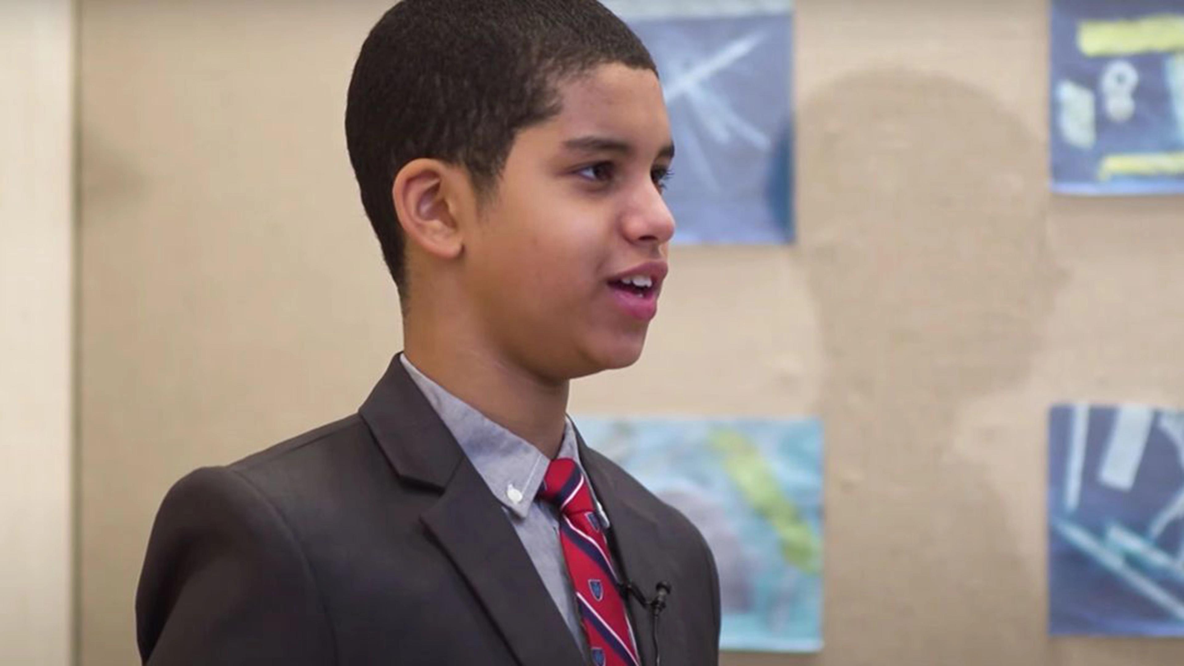 Met visitor, Ian, age 11, speaks with an educator offscreen in front of a display case of artworks