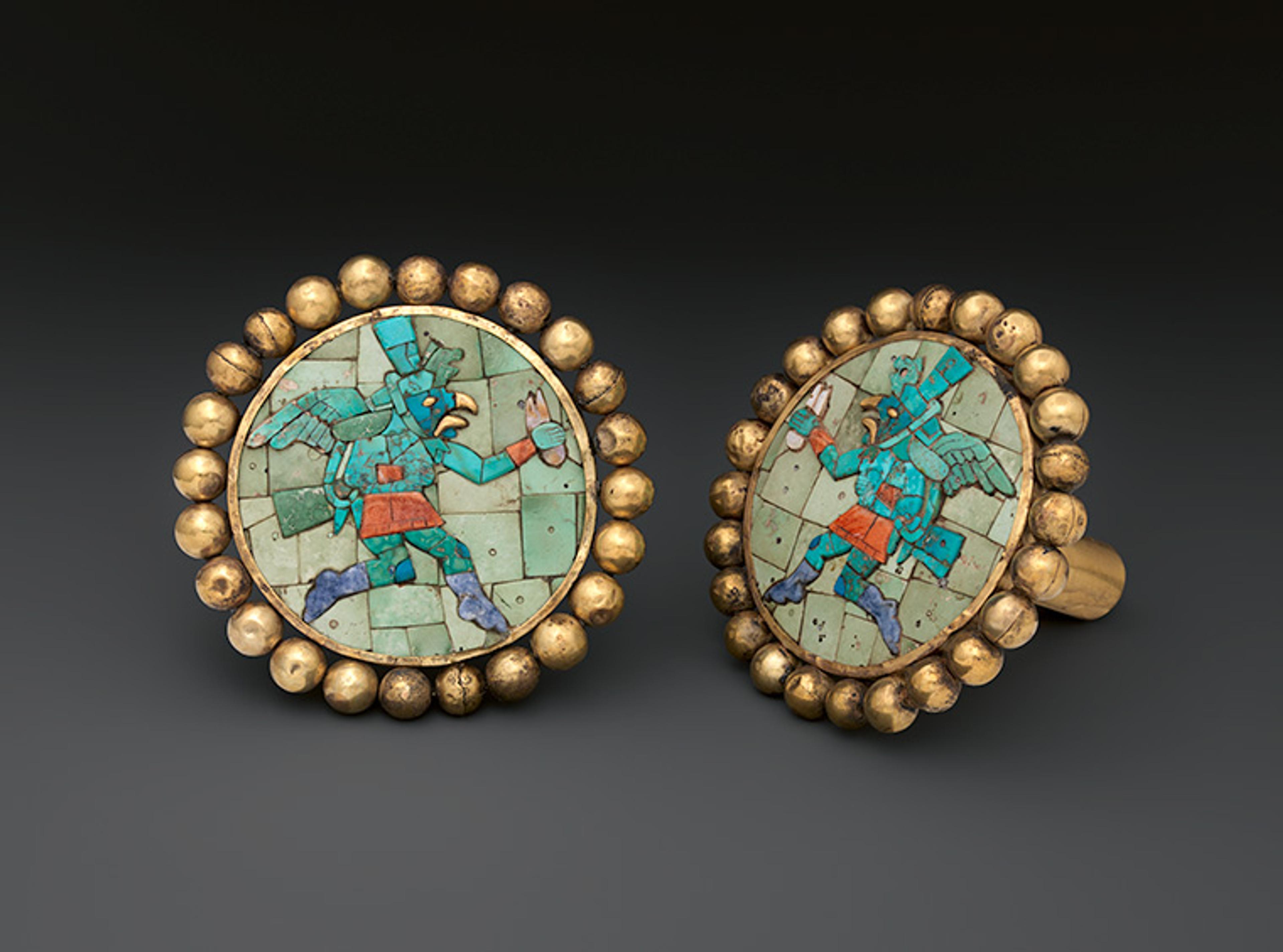 The earflares shown in pair. One of the ornaments is frontal, the other is shown at an angle giving a glimpse of the back.