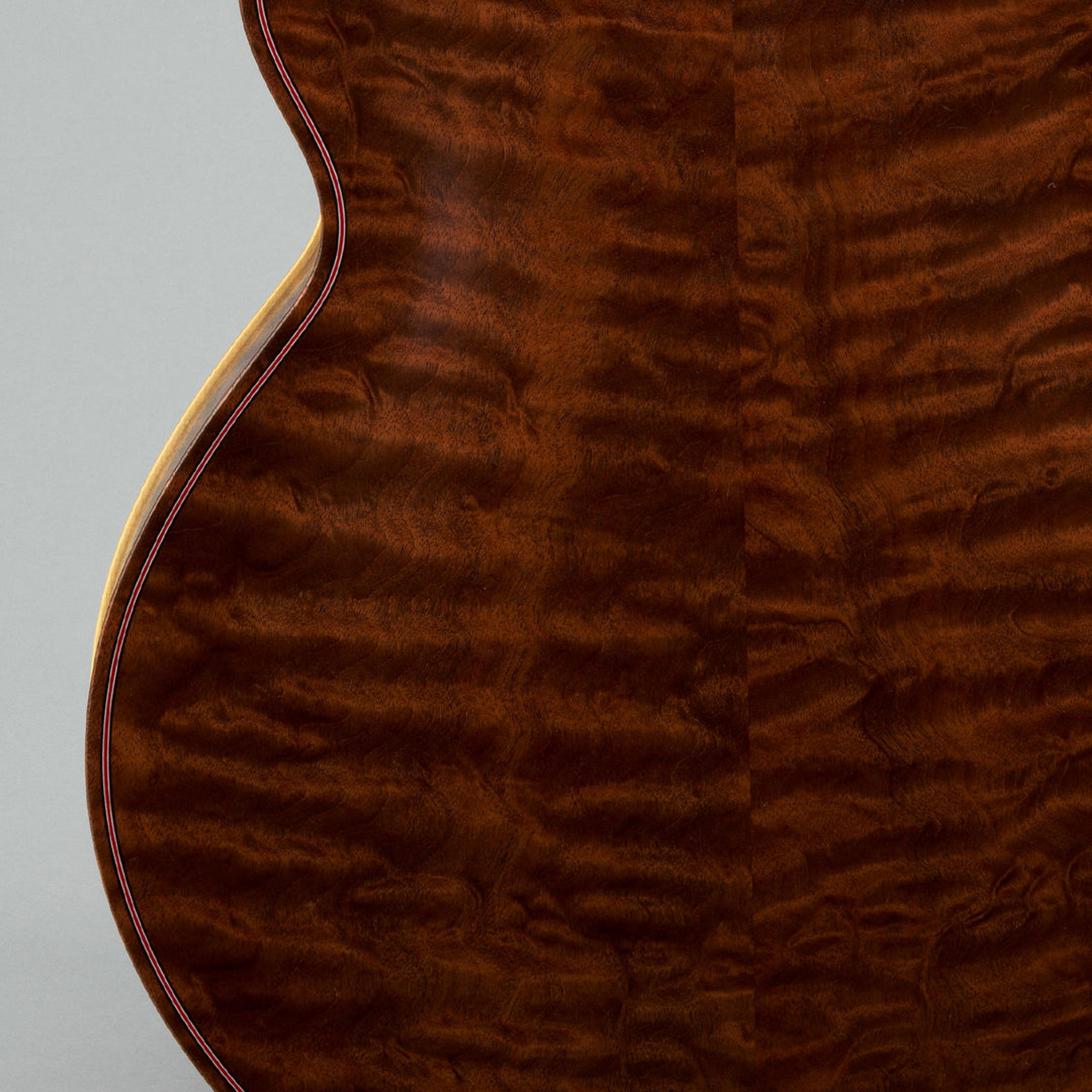 Detail of a guitar backside. The shiny mahogany wood has varying shades of brown, creating an almost marbled effect.