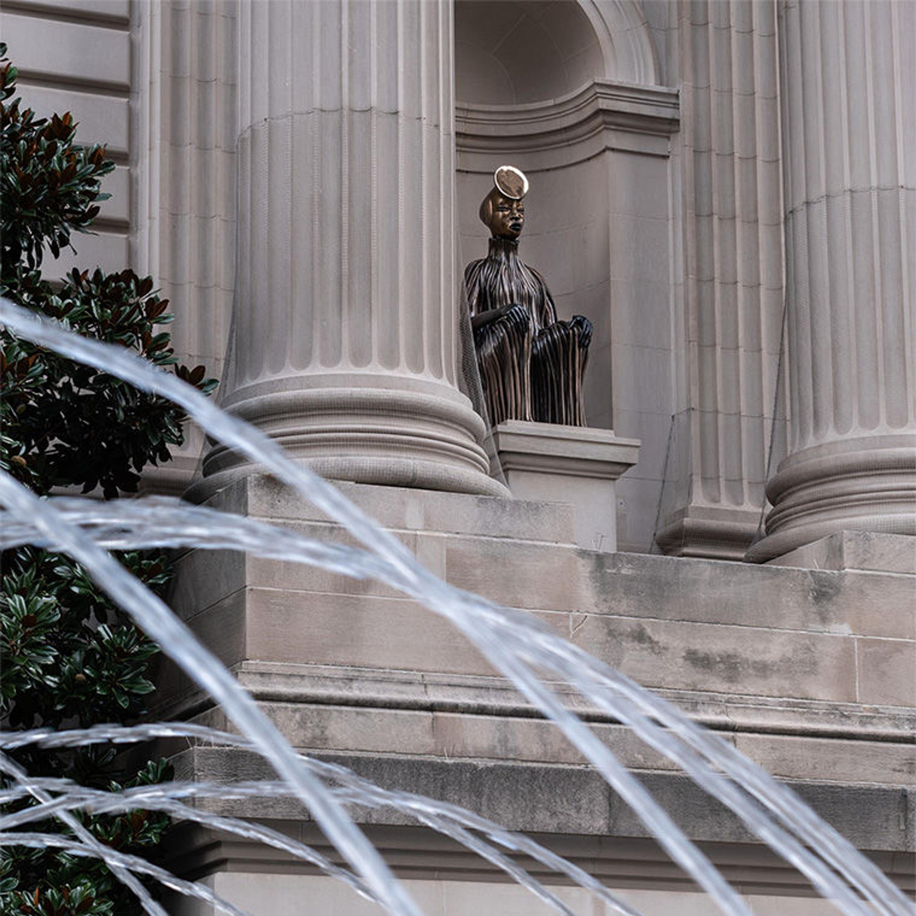 A bronze figure sits in the Metropolitan facade