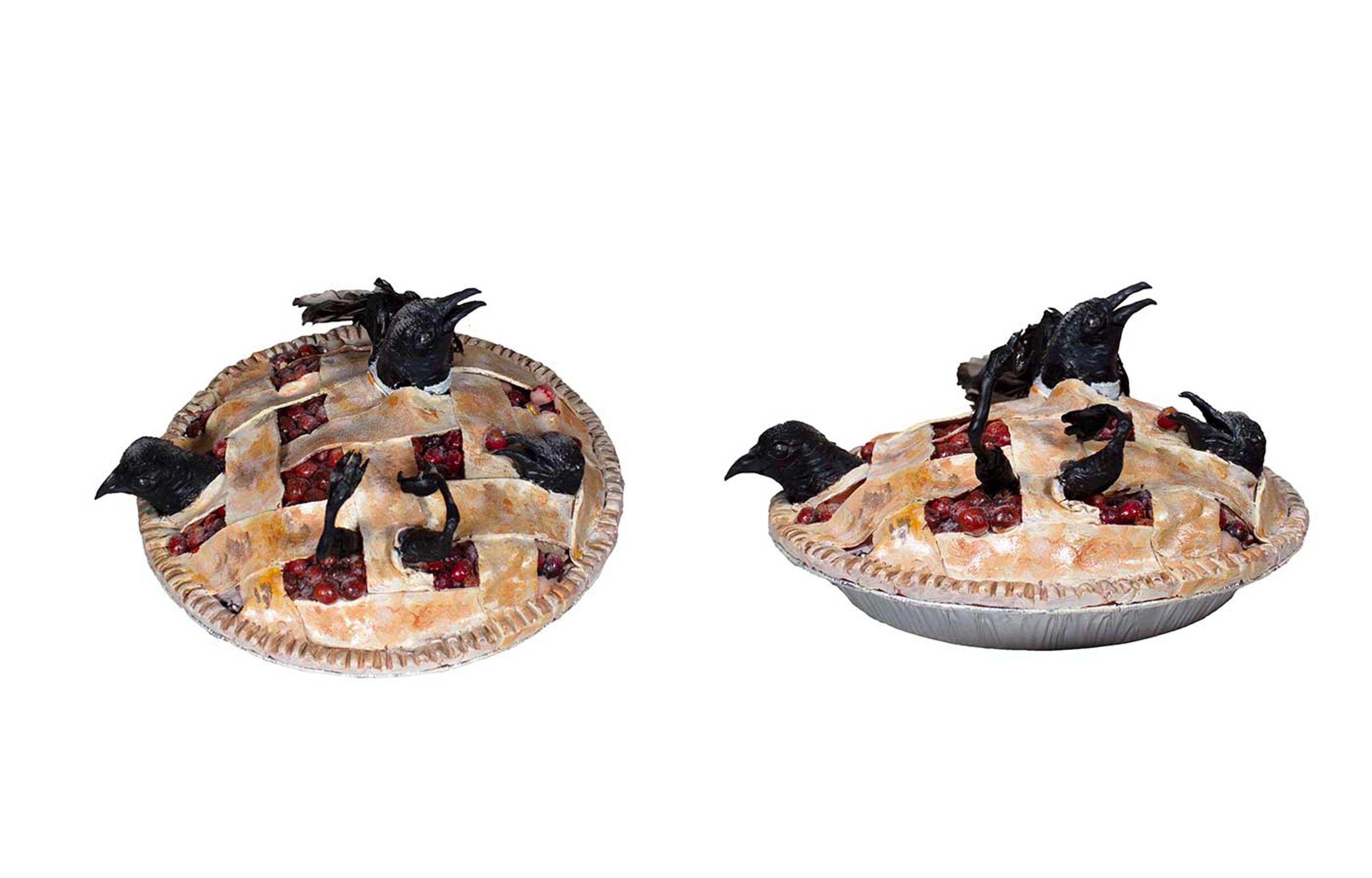 Sculpture of black birds bursting out of a pie with a lattice top.