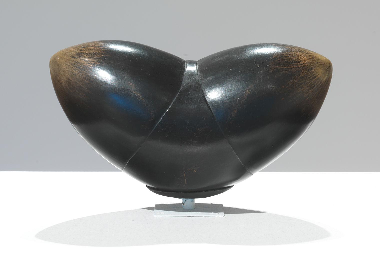 Dark bronze sculpture with two round anthropomorphic portruding forms coming out symmetrically and upwards.