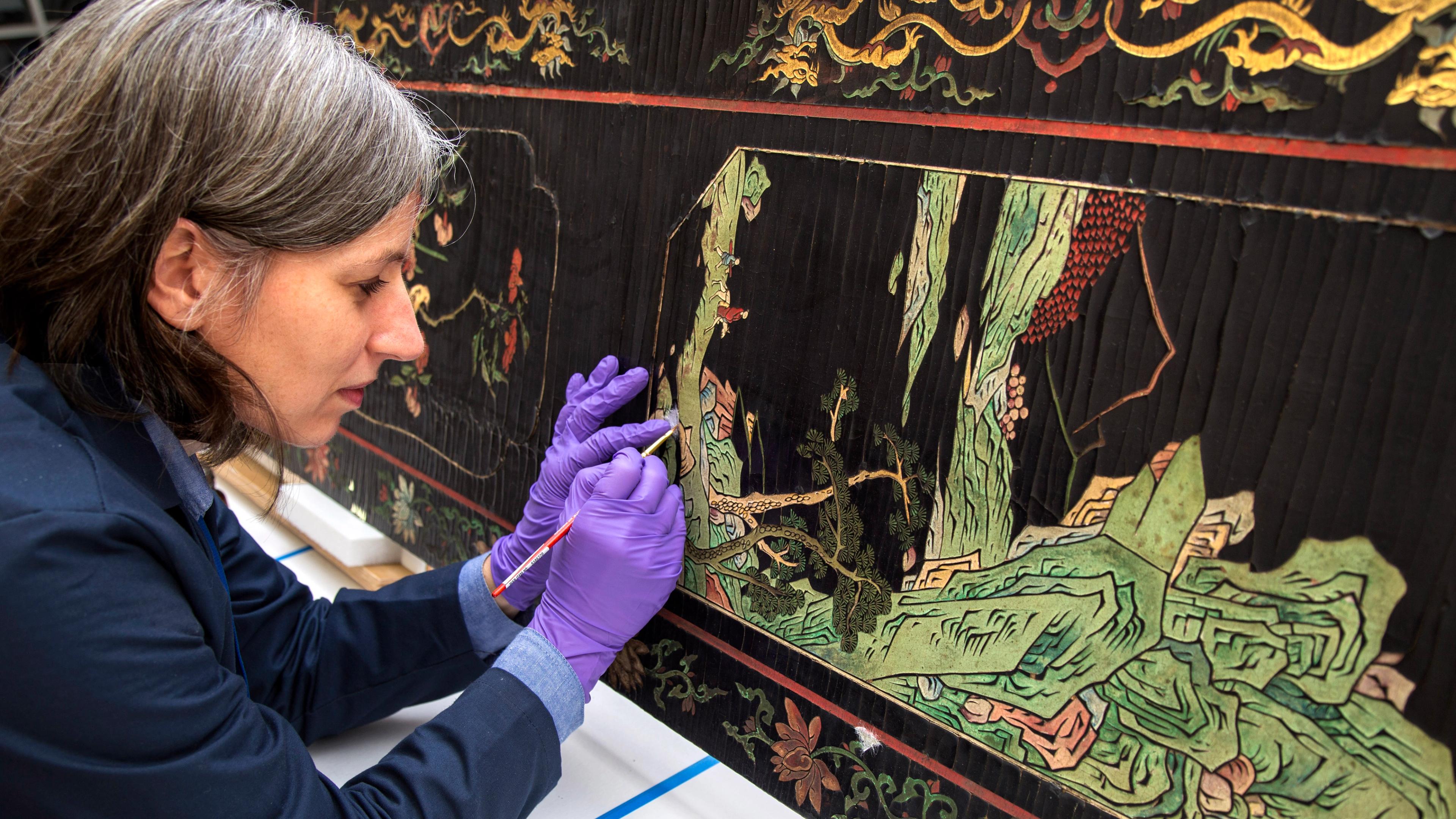 Conservator working on a piece of East Asian furniture.