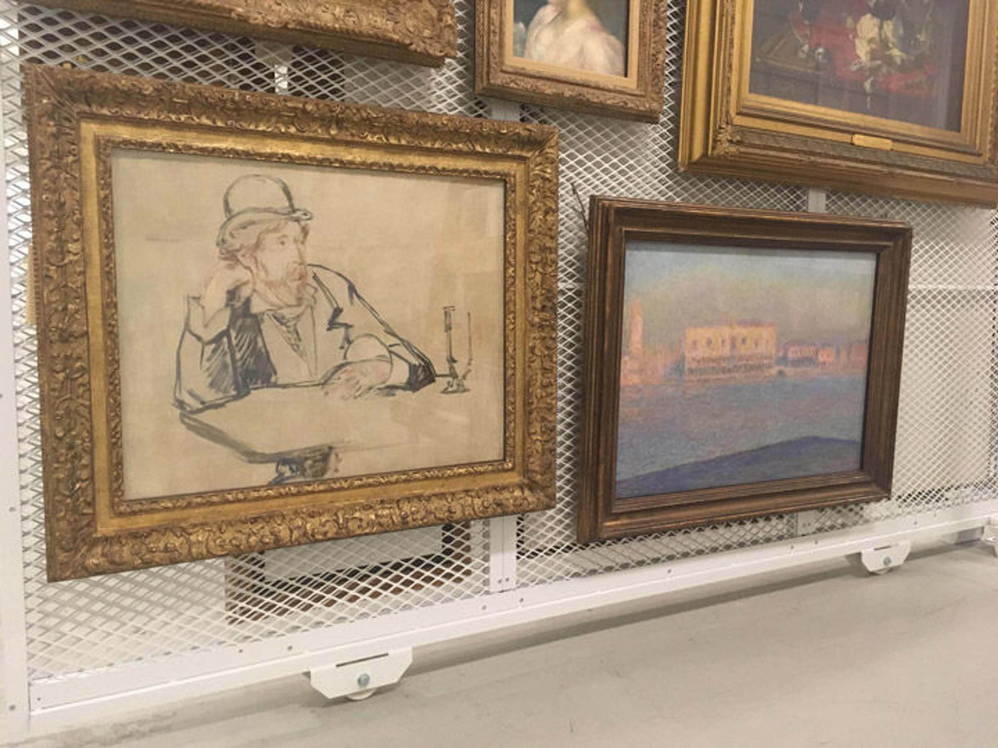 View of several European paintings housed on a wall in a storeroom