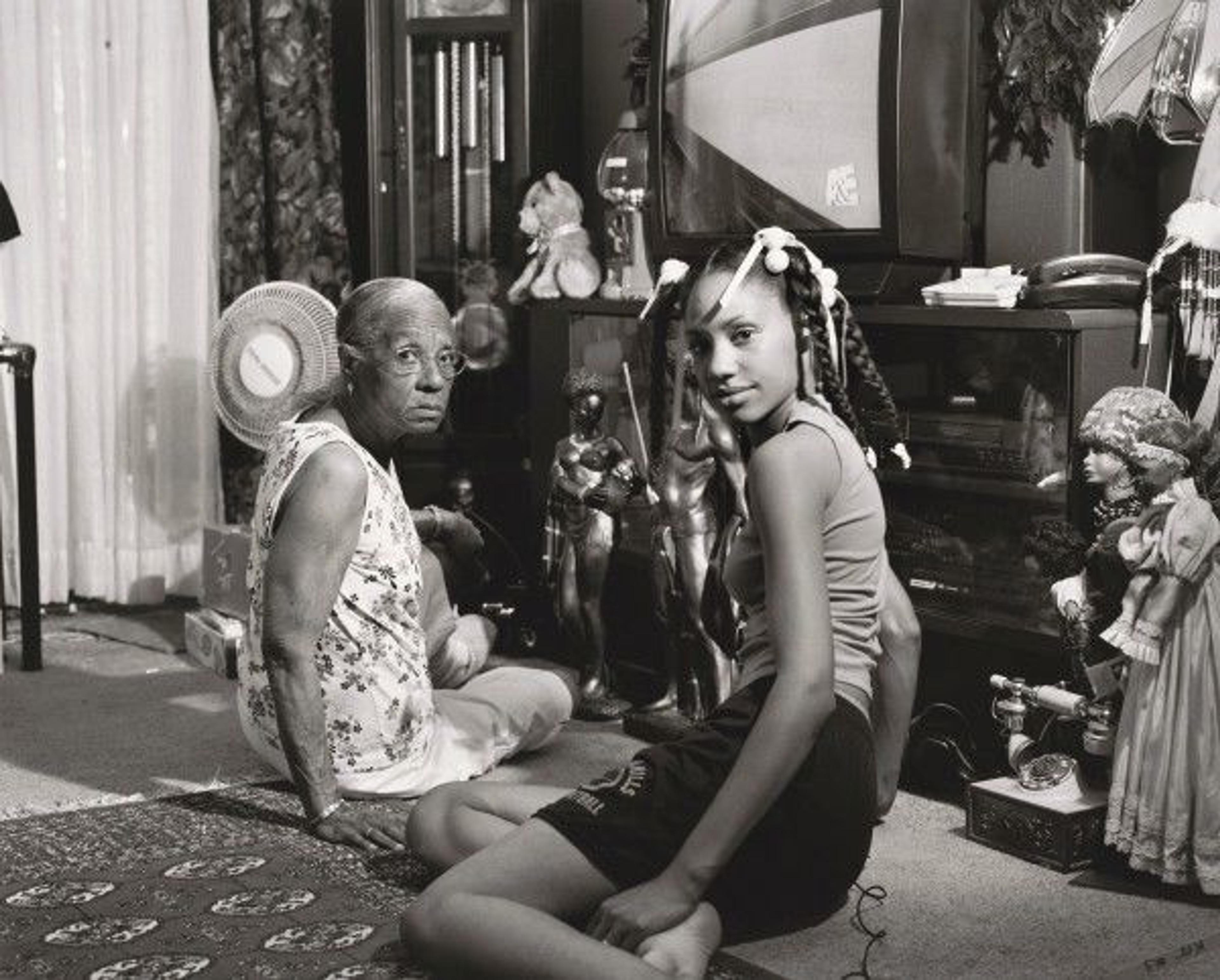 A young Black girl sitting on the floor of a house with her grandmother