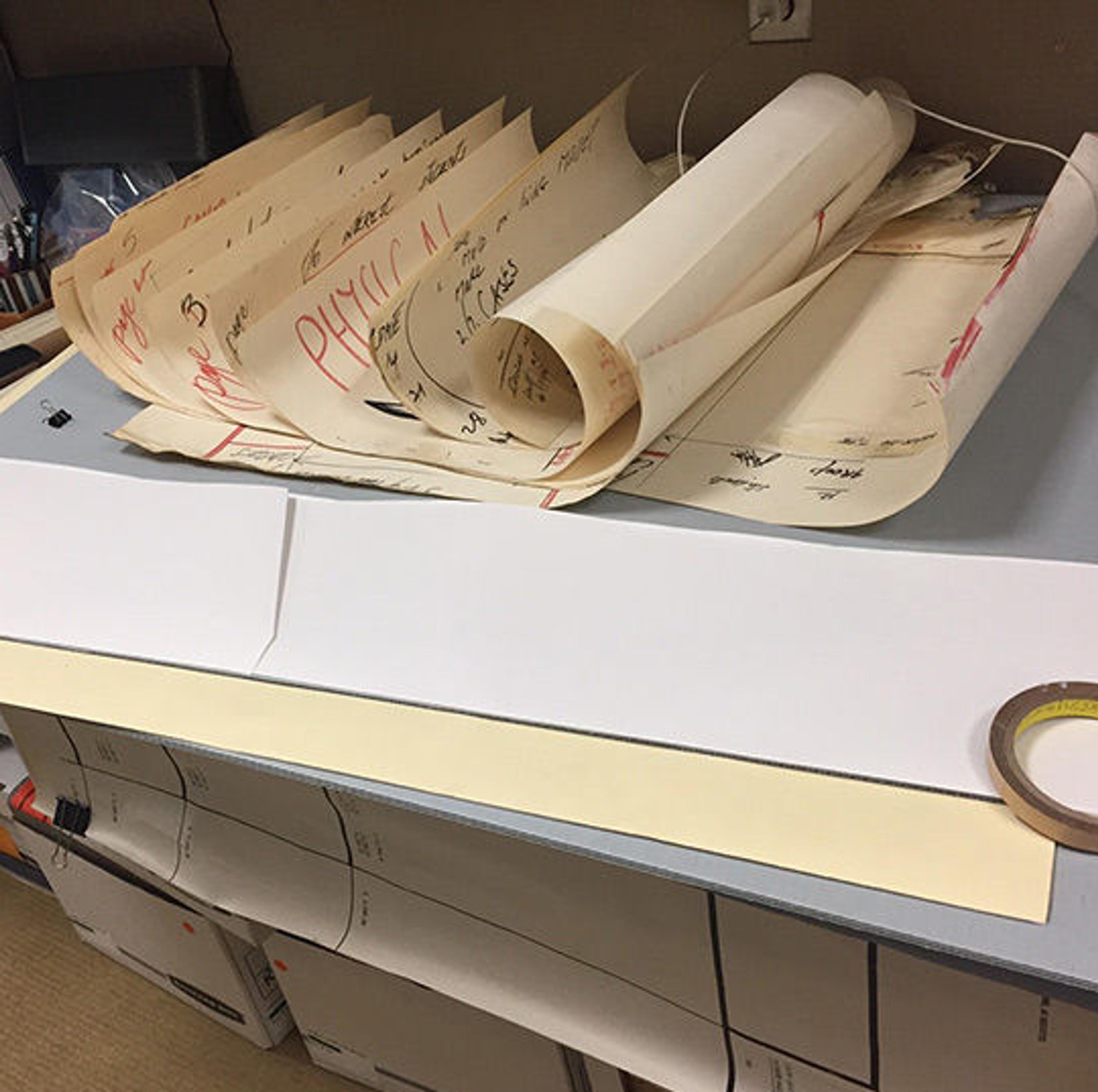 Rolls of oversize papers atop a table.