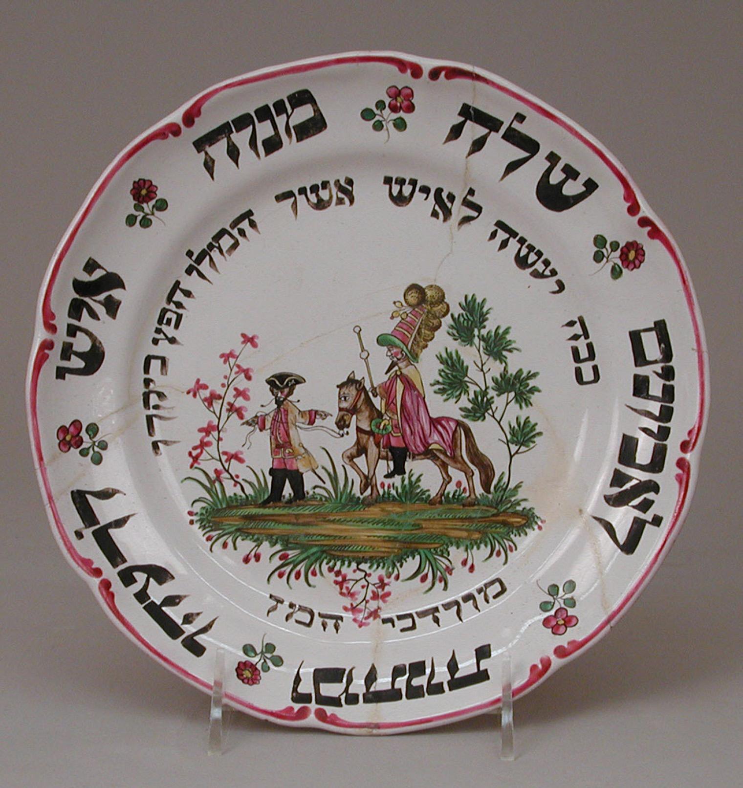 Ornate plate with Hebrew script at center, surrounded by vibrant pink floral patterns and green leaves on a white background.