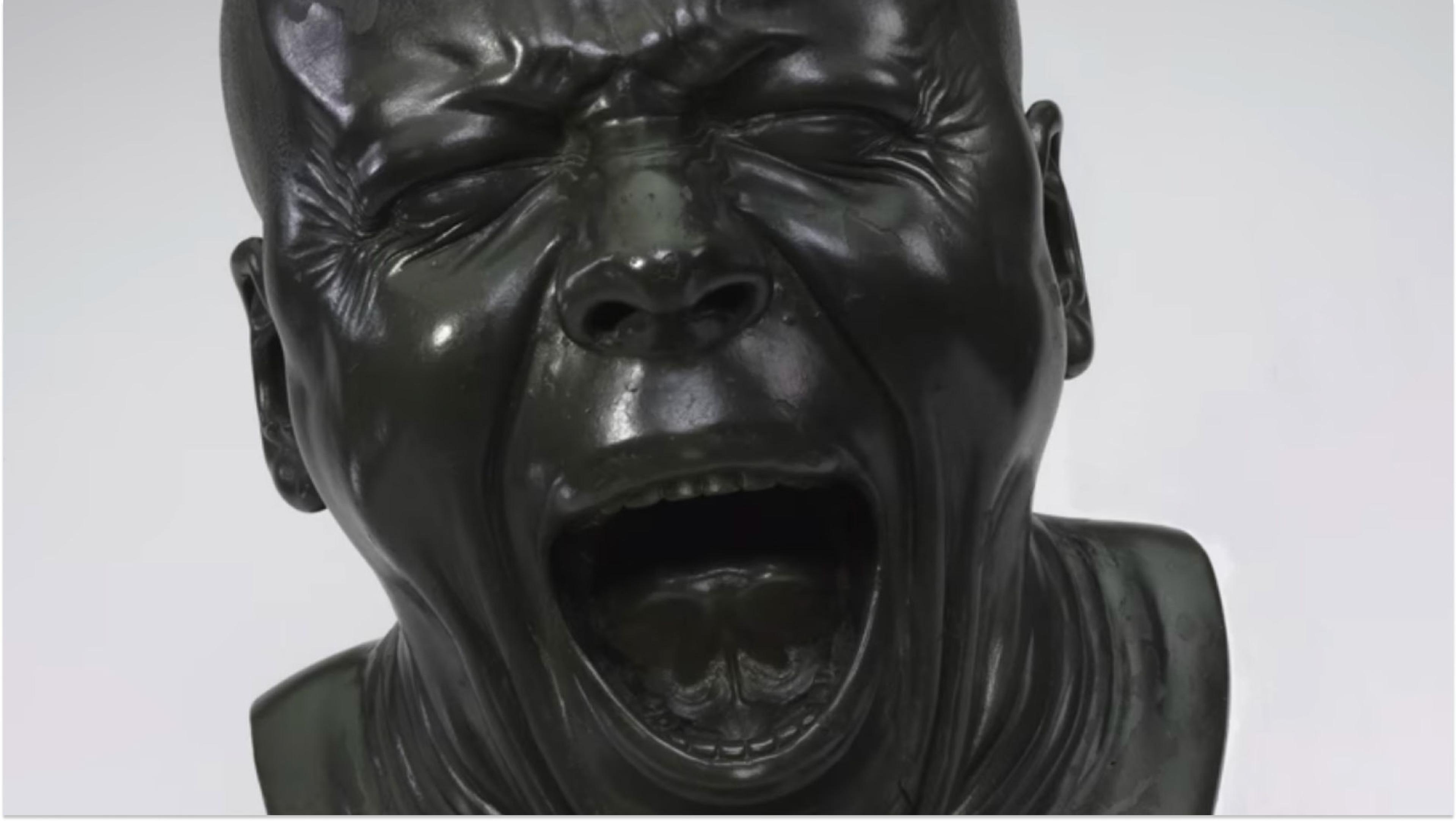 Dark grey bust is captured mid-scream. Behind is a white-grey background.