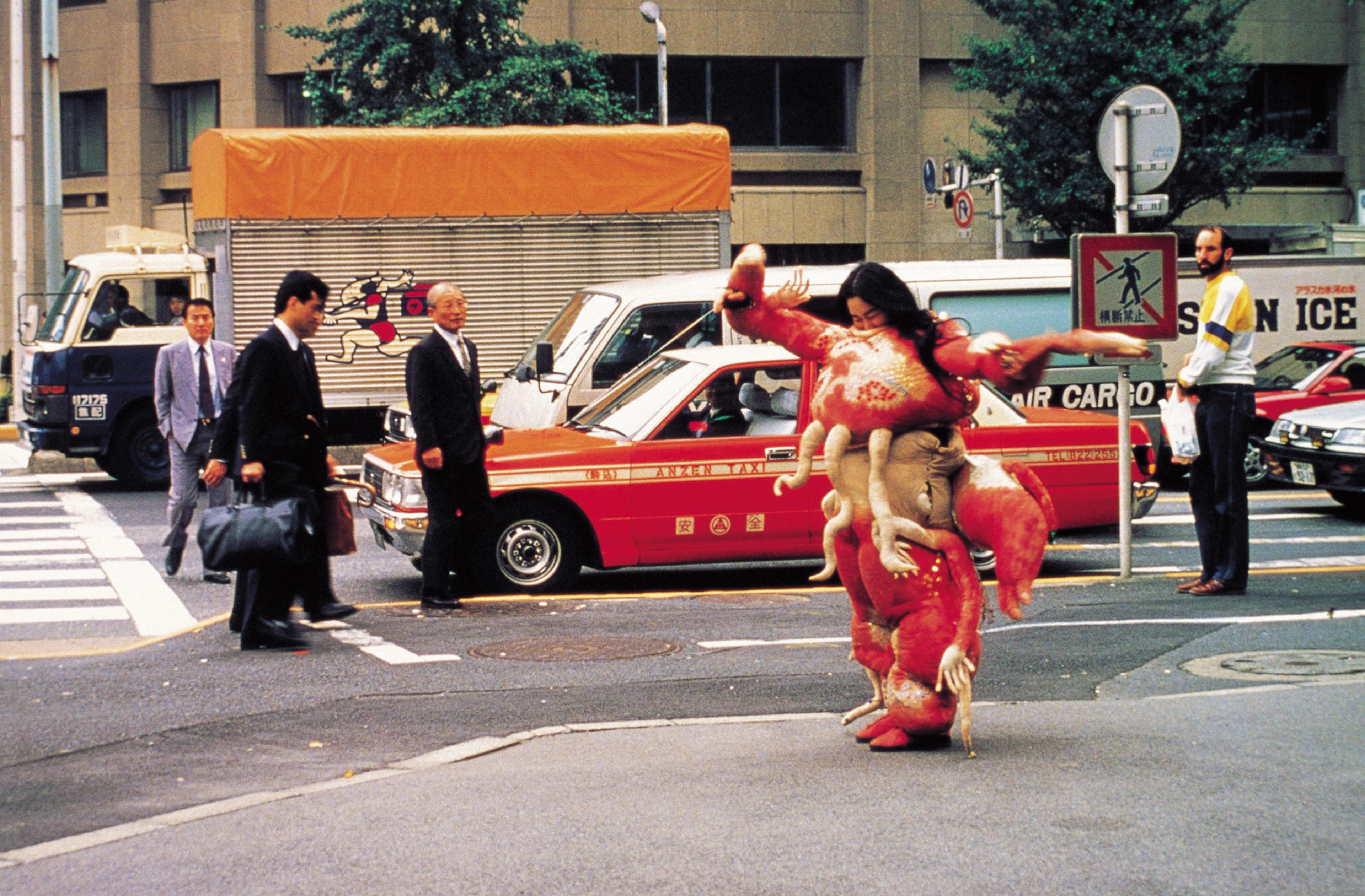 Woman standing on the edge of the sidewalk, weaing a tranditional asian costume.
