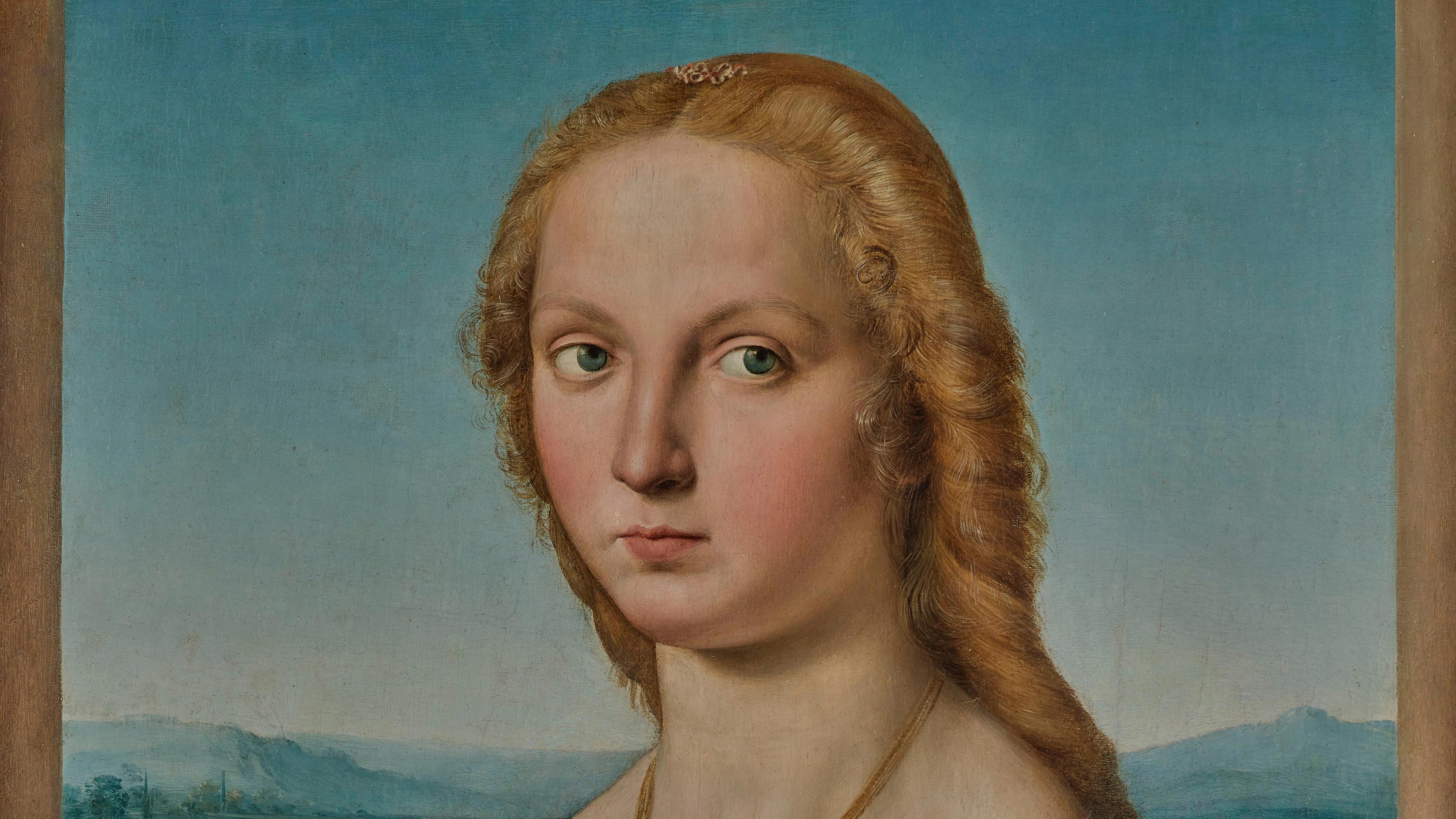 Portrait of a blonde, stern-faced woman with round cheeks against a blue, mountainous background.