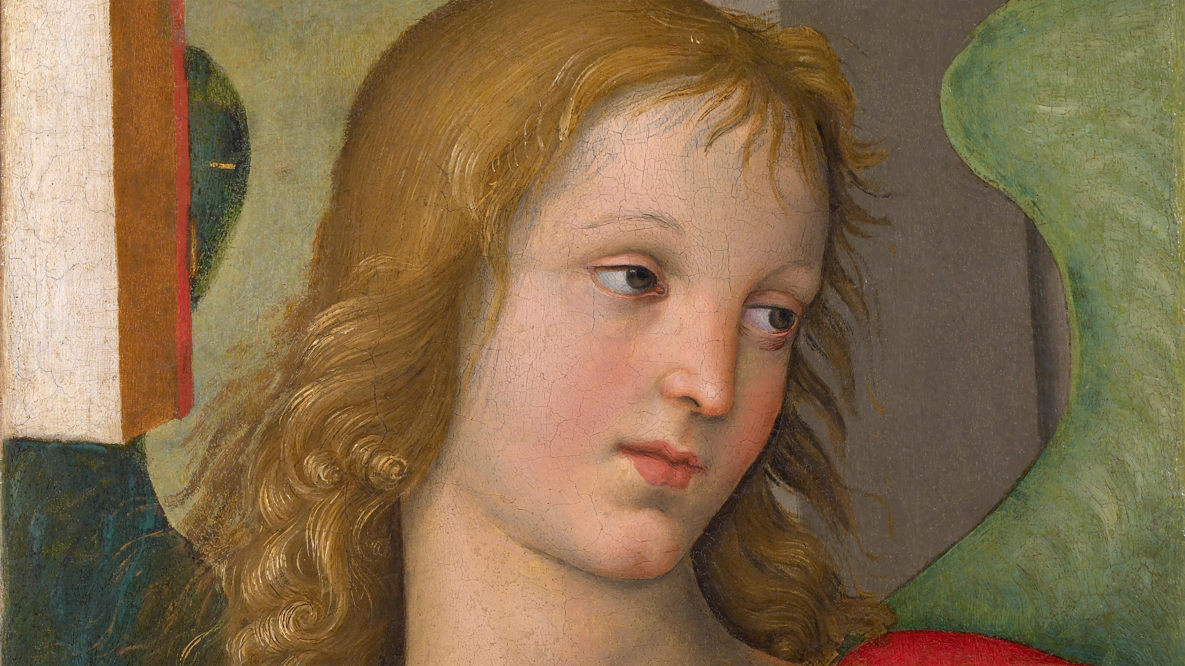 A blonde, angel looking downwards with a green wing coming out of its back. The angel is draped in a white and red robe.