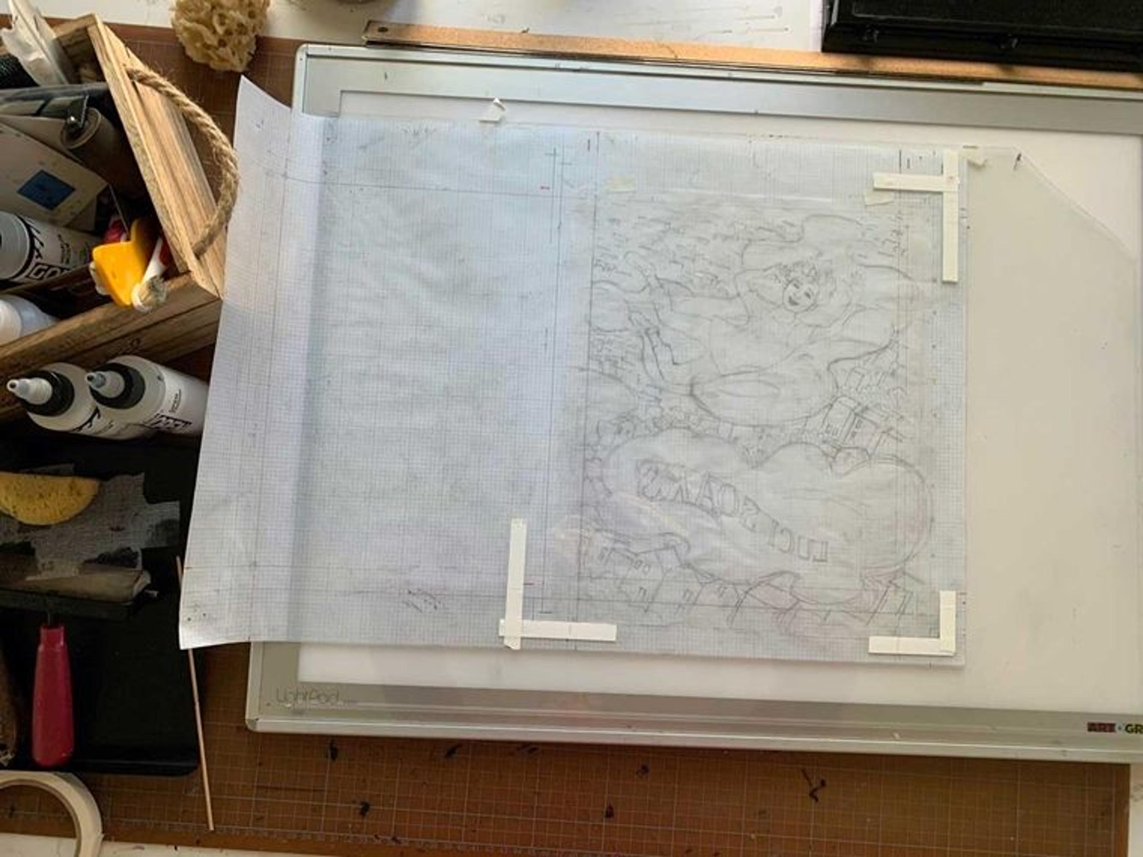 A pencil sketch of the mirror image of the cover of Luci Soars on tracing paper sits on a workbench. The corners of the page are registered with pieces of white tape.
