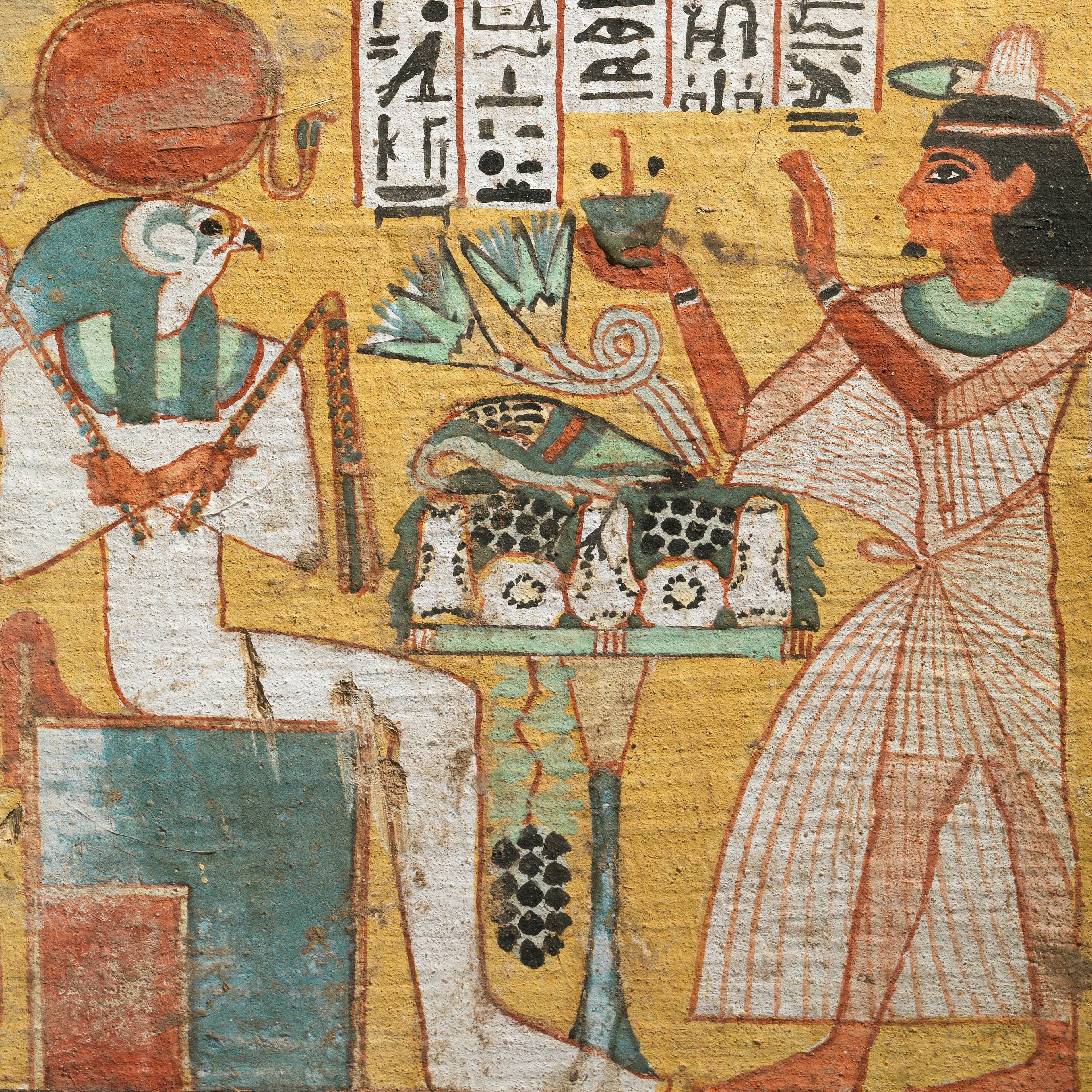 An ancient Egyptian painting of a falcon-headed god being approached by a man holding a vessel