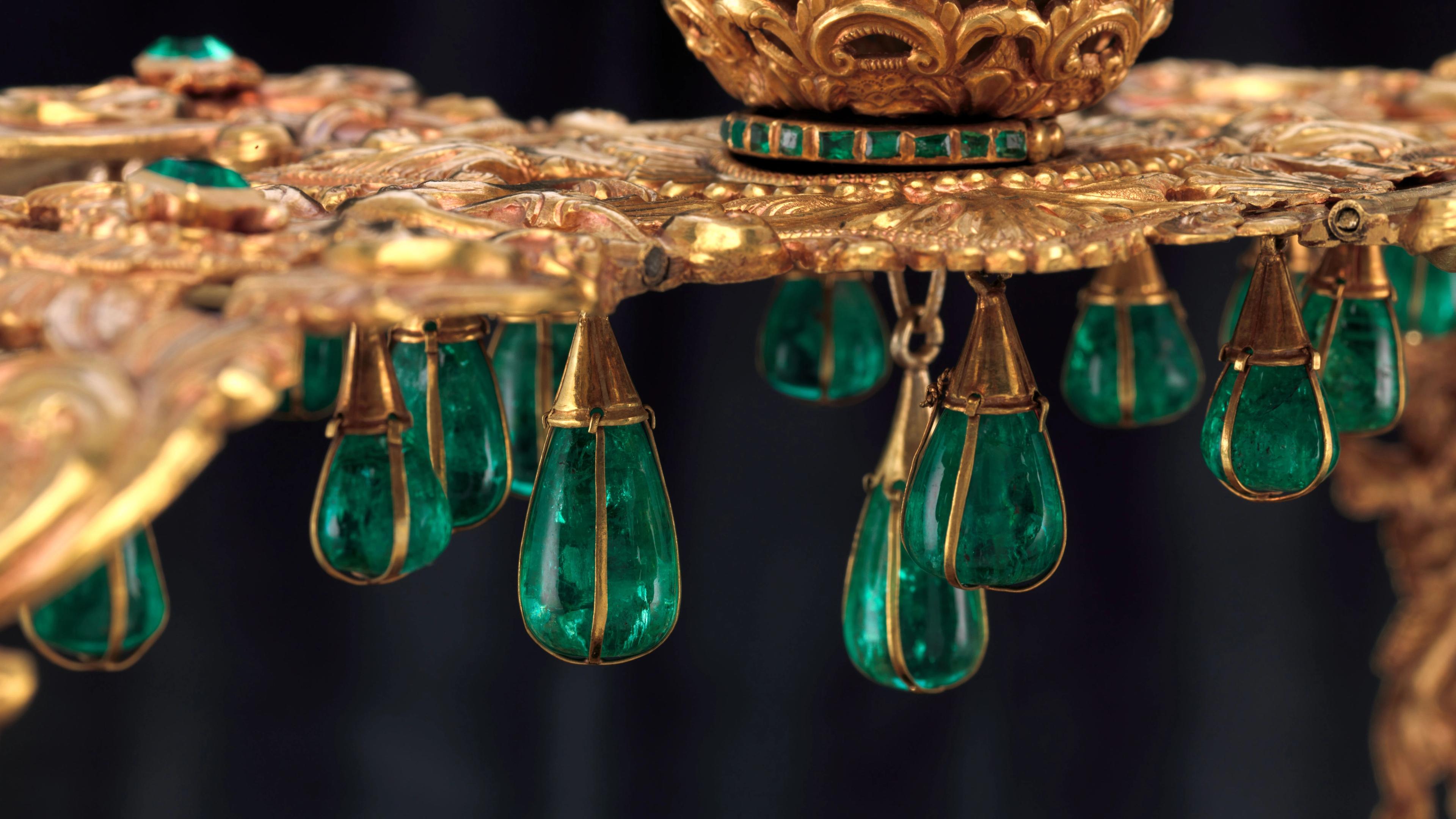 Close-up of the "Crown of the Andes" showing intricate goldwork and large, teardrop-shaped emeralds suspended in delicate gold settings.