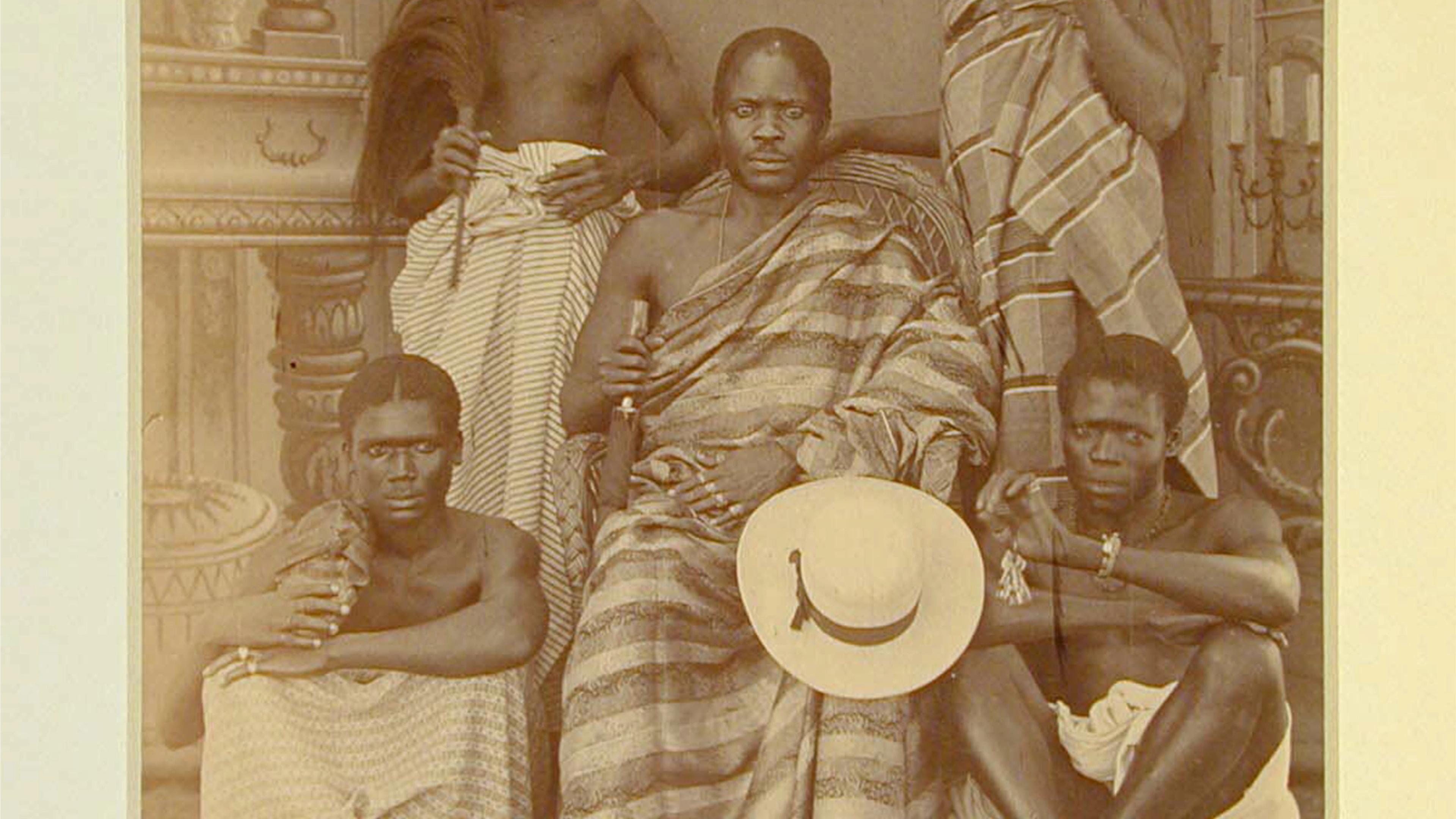 Five men posing for a photograph, surrounding a seated central figure