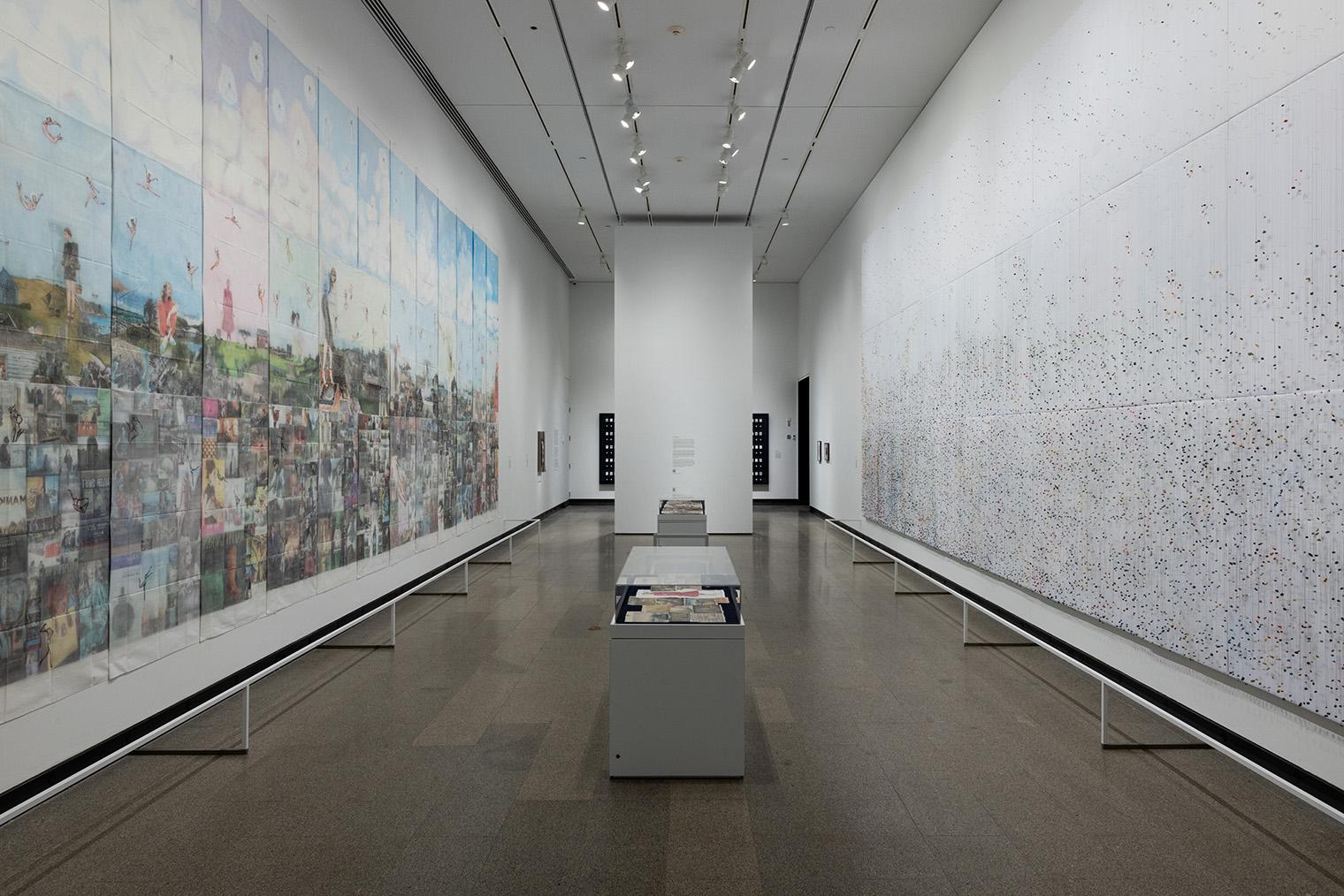 A spacious art gallery features two large murals on opposite walls. The left mural is vibrant and detailed, while the right is more abstract and speckled.