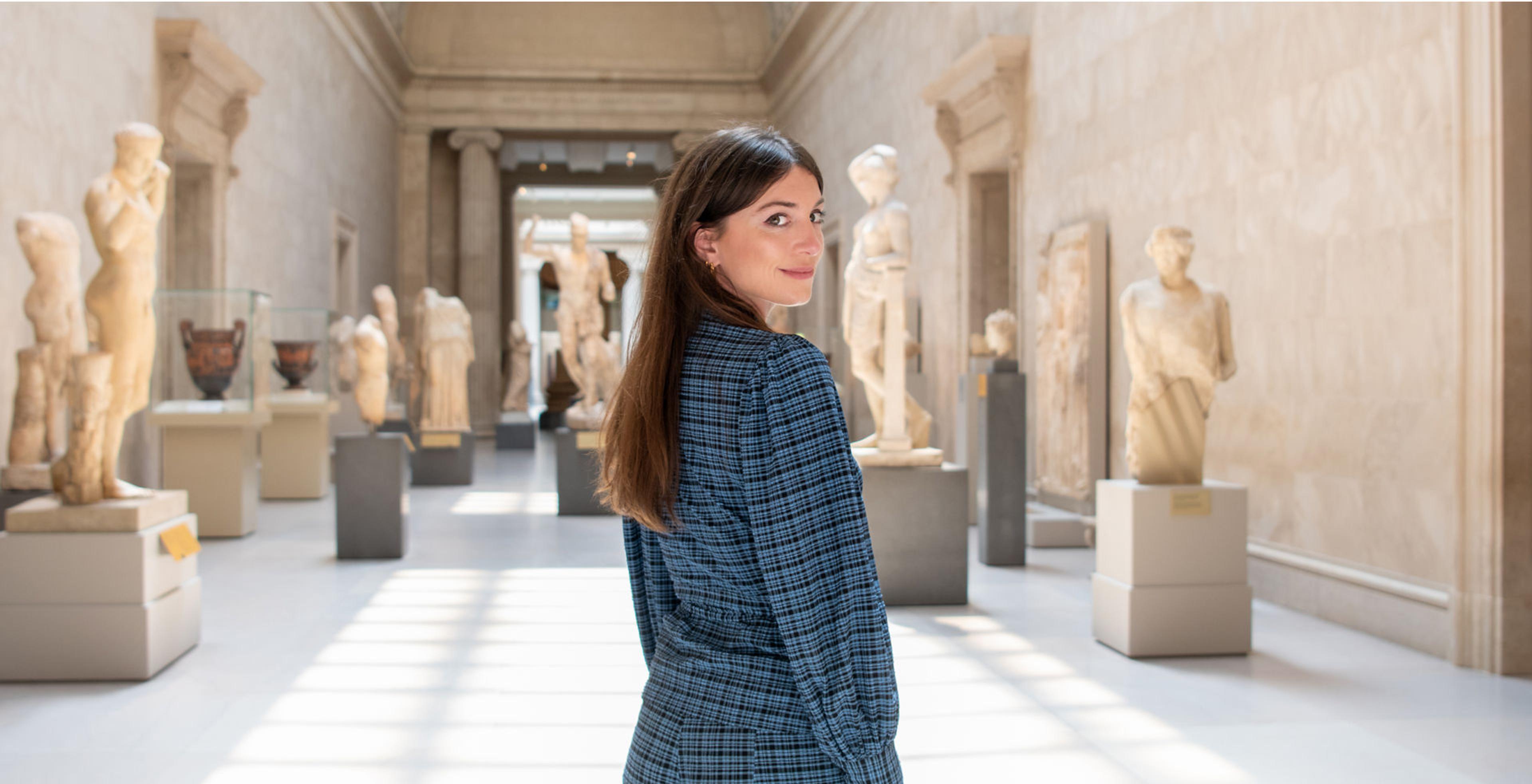 Katy Hessel stands in the sunlit Greek and Roman galleries at The Met Museum.