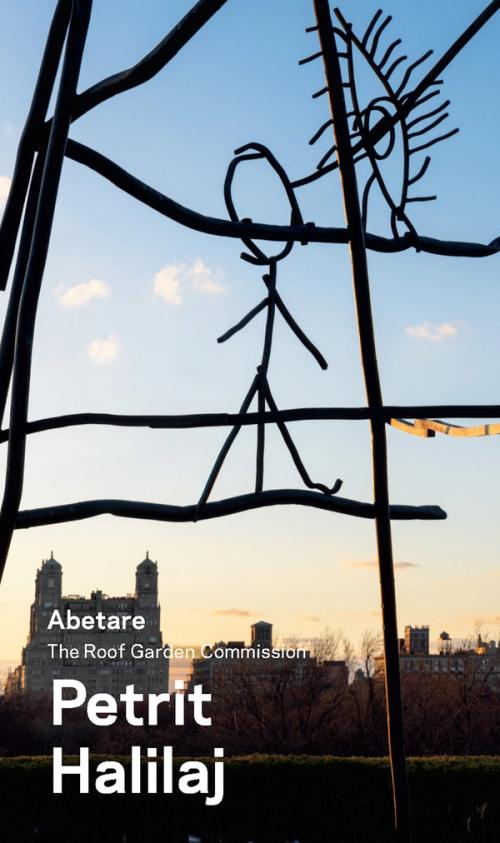 a sculpture of a stick figure and an eye perched on a metal branch against a skyline at sunset