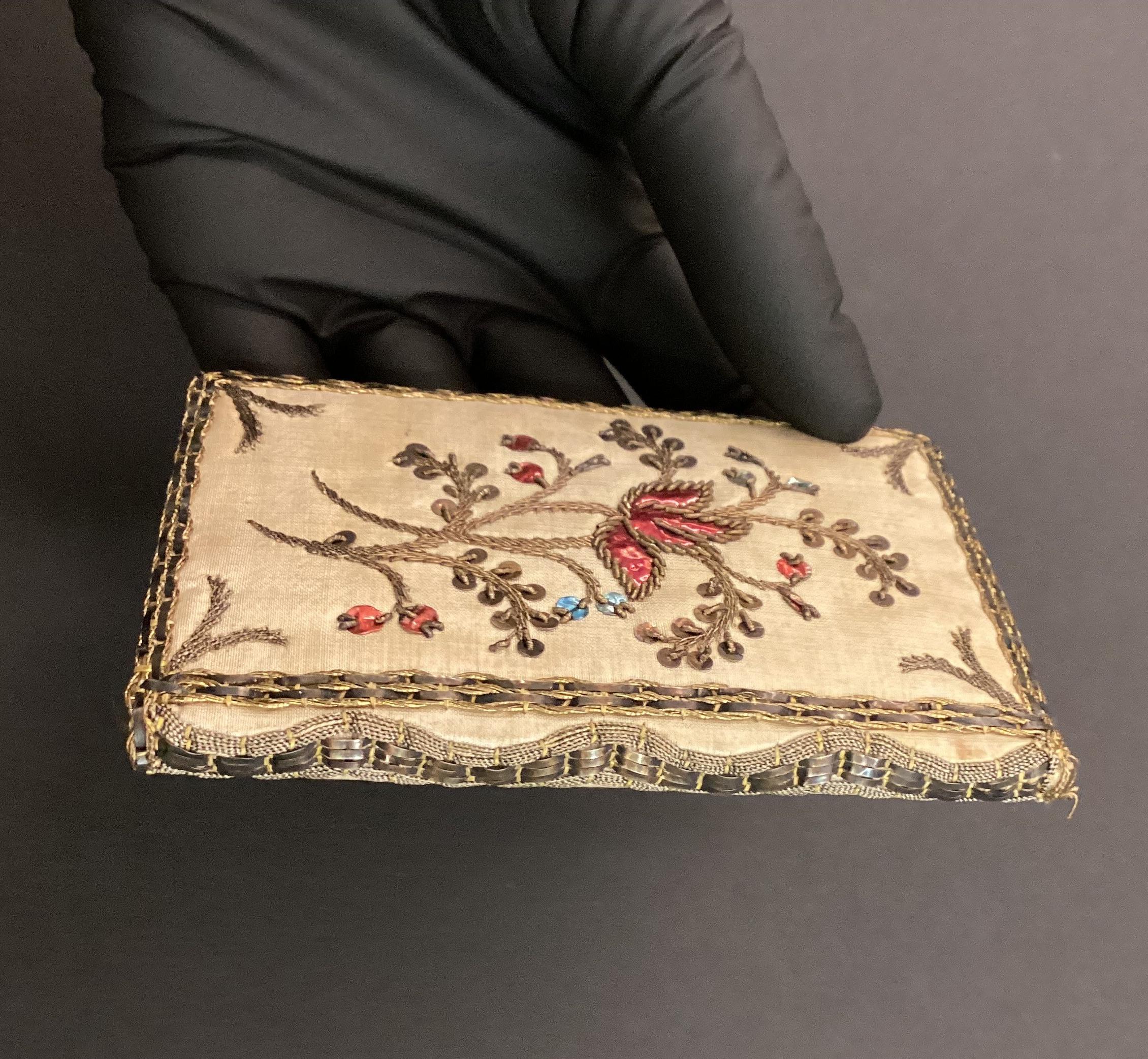 Gloved hand holding small book