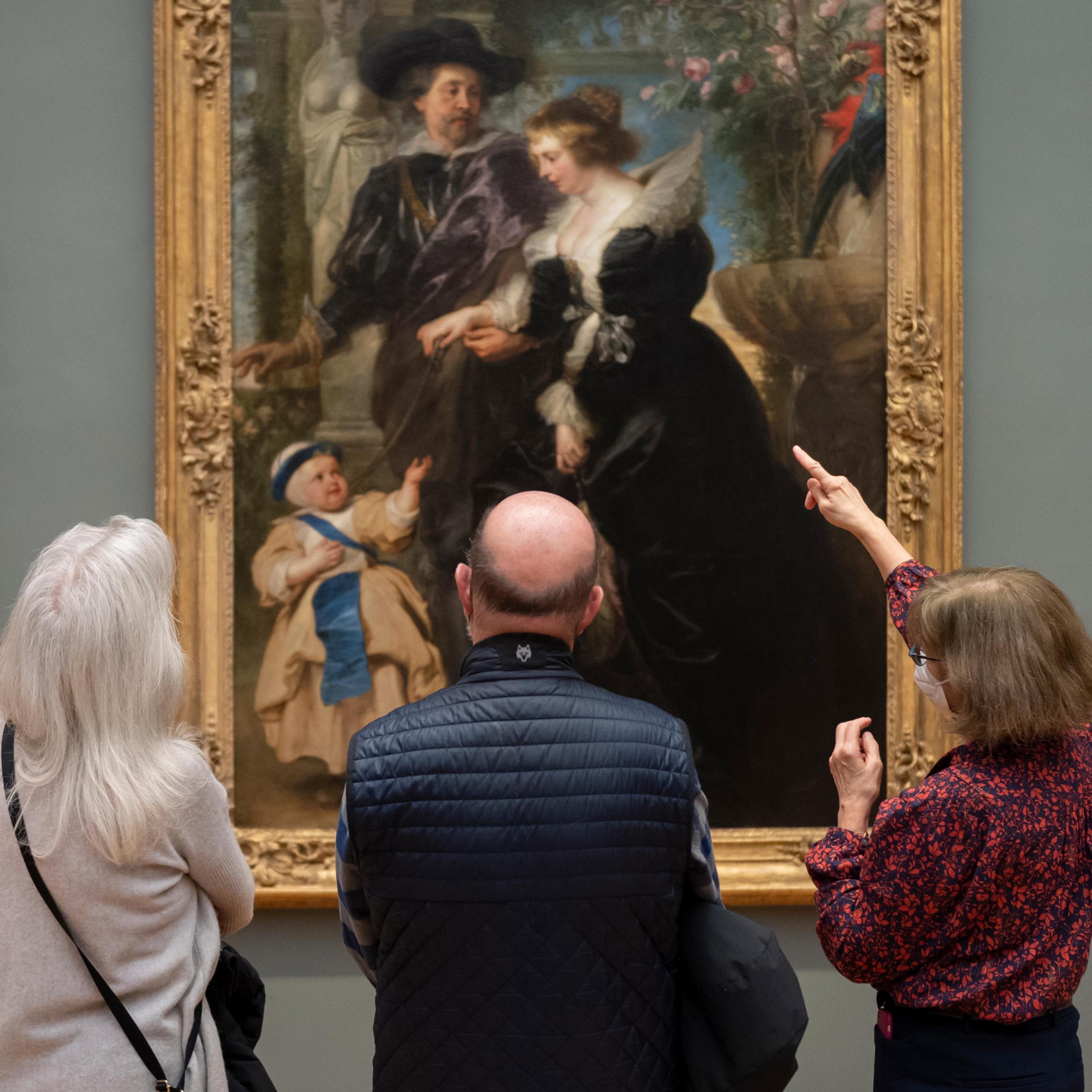 A tour guide points to details on a painting