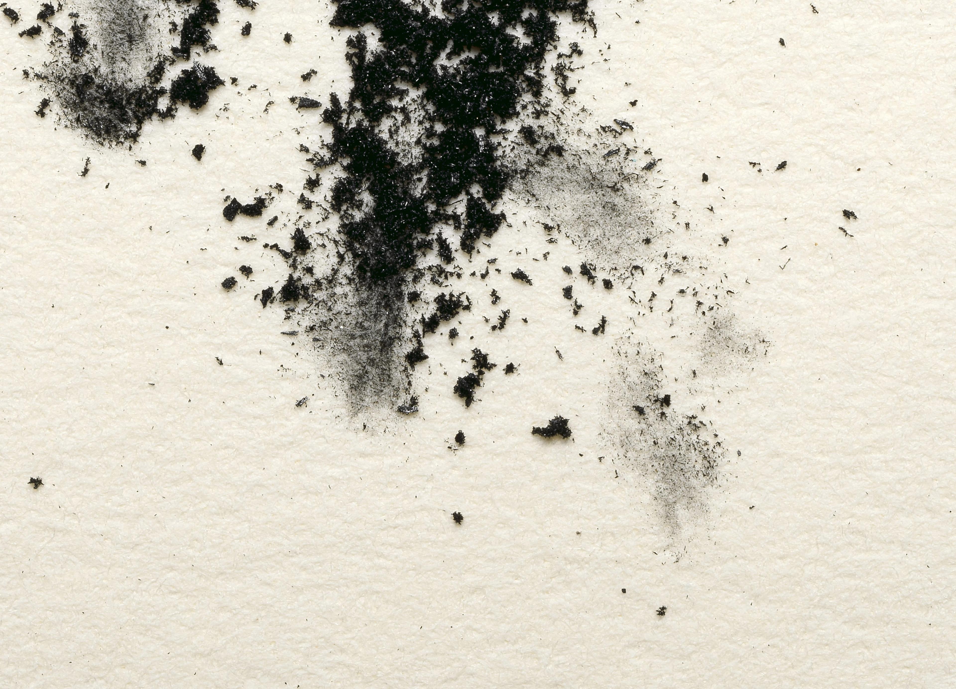 Charcoal powder messily scattered over a lightly textured white surface.