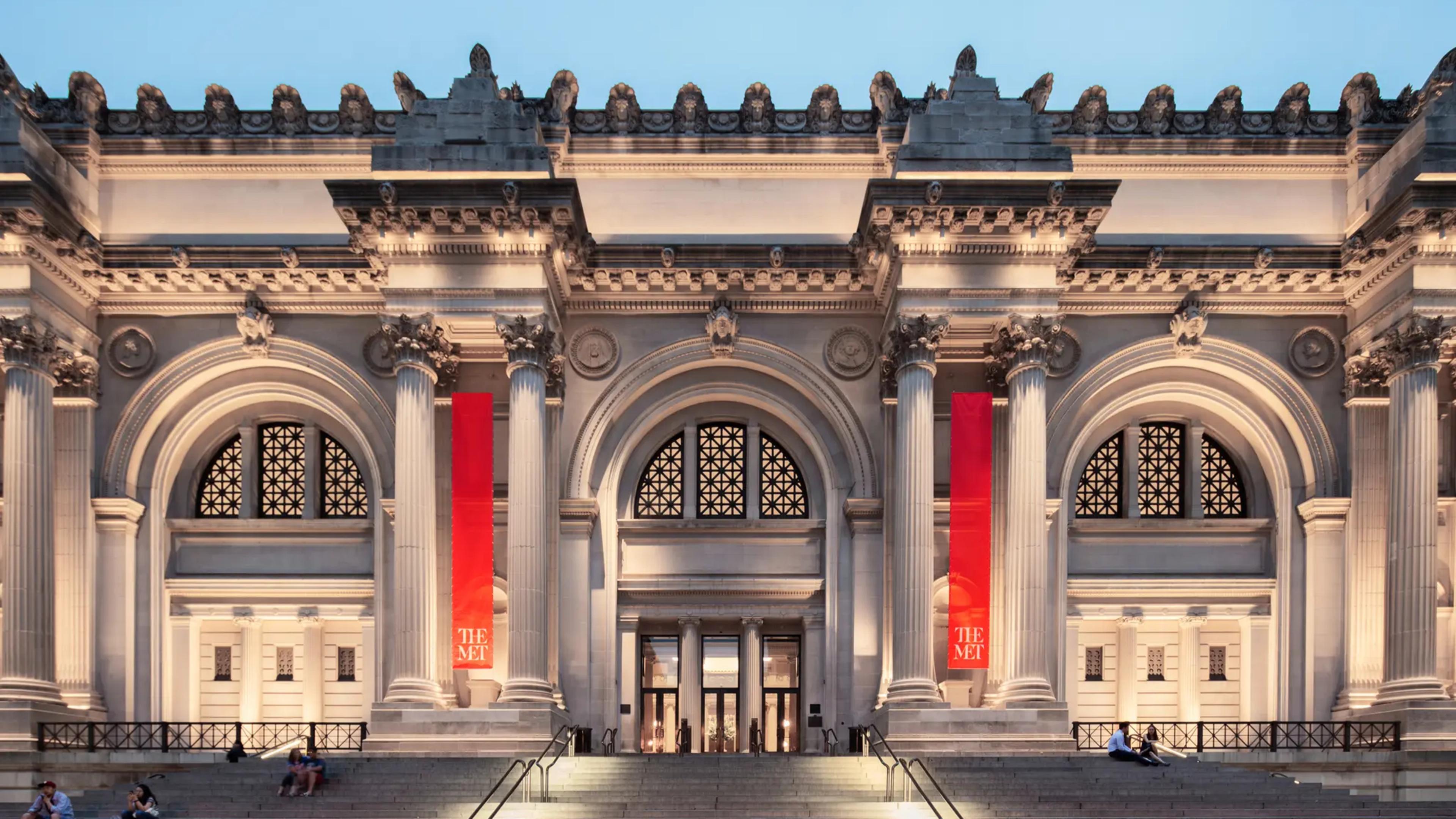 The Met Fifth Avenue facade lit dramatically in the evening.